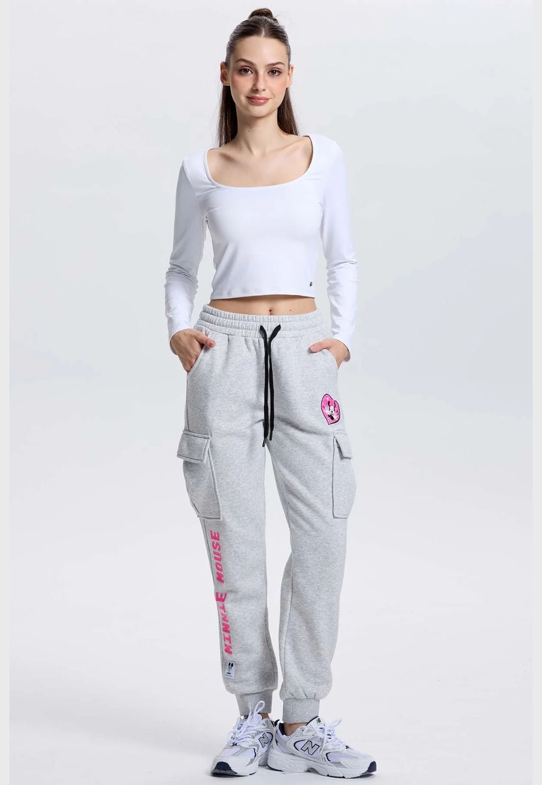 Pantalón jogger gris con estampado de Minnie Mouse en un corazón rosa y texto 'MINNIE MOUSE' en fucsia, ideal para fans de Disney.