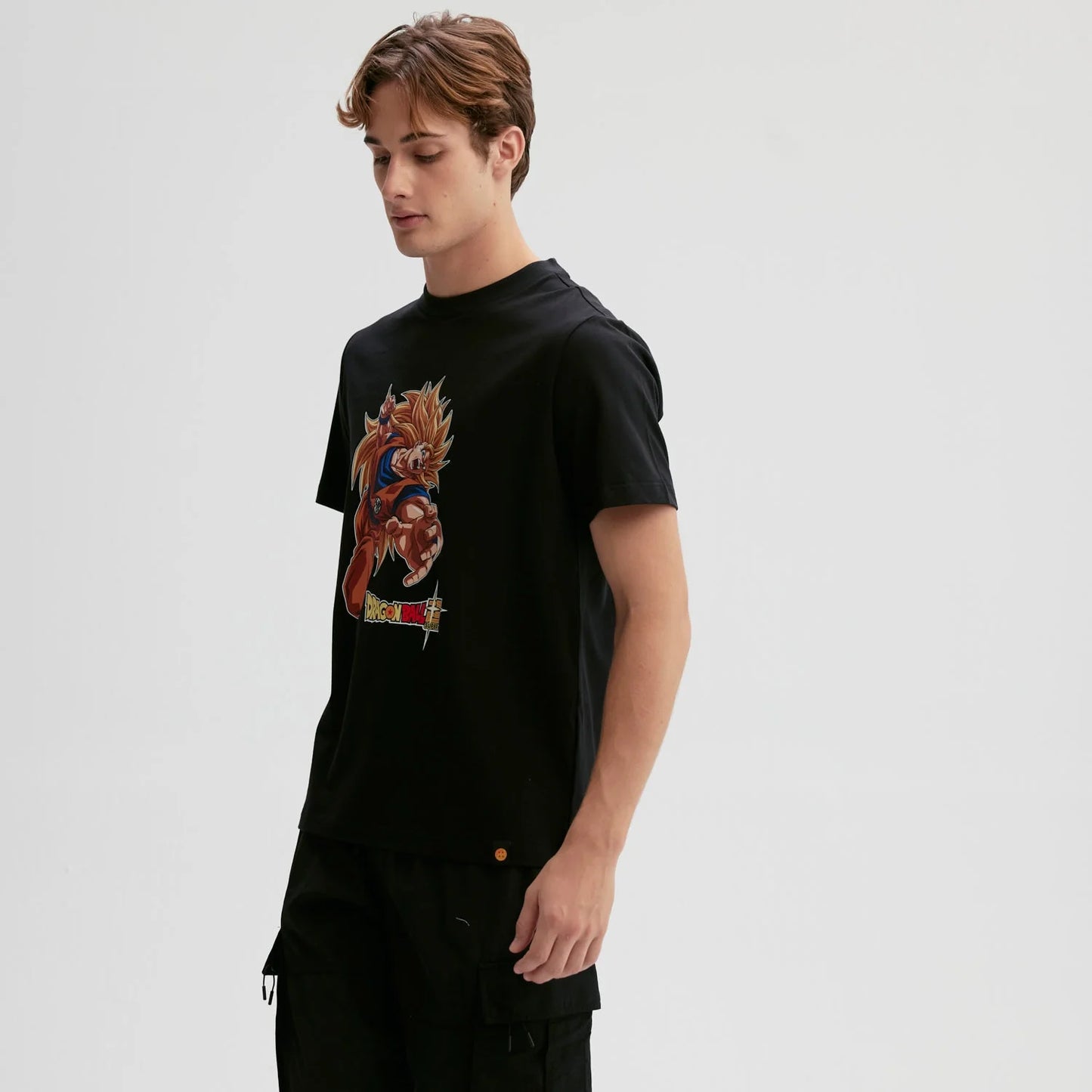 Polera negra de algodón con ilustración vibrante de Goku en Super Saiyan, mostrando su icónica pose de ataque, con el logo de Dragon Ball en la parte inferior.