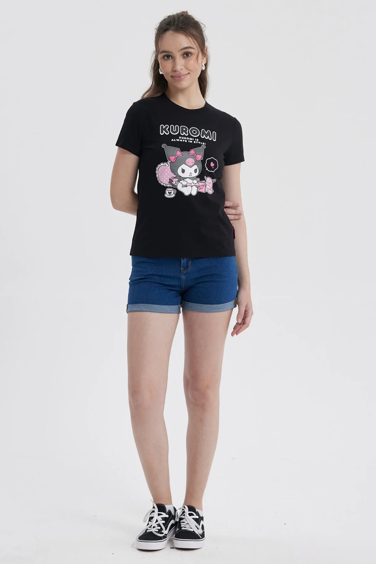 Polera negra de algodón con estampado de Kuromi, personaje de Sanrio, sentada en un sillón rosa con un té, rodeada de detalles en rosa y texto 'KUROMI IS ALWAYS IN STYLE'.