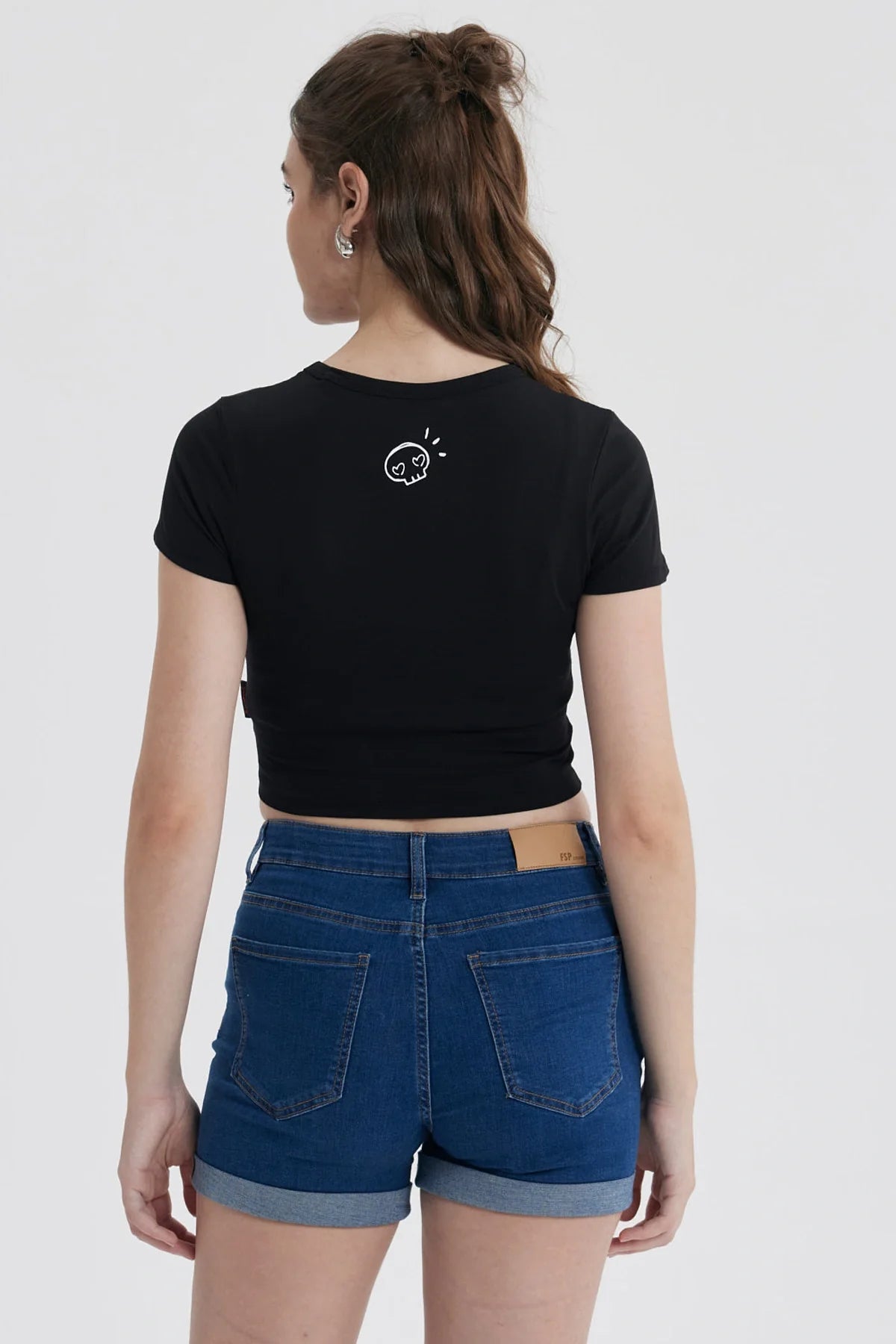 Polera negra de algodón con un diseño minimalista de Kuromi, una traviesa calaverita de Sanrio, mostrando su icónica expresión juguetona y sosteniendo cerezas.
