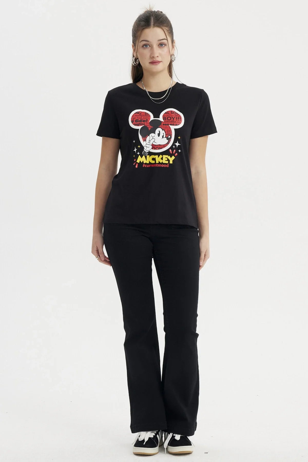 Polera negra de Mickey Mouse con un diseño gráfico vibrante que muestra al icónico personaje rodeado de burbujas de texto en rojo y amarillo, expresando su personalidad alegre y divertida.