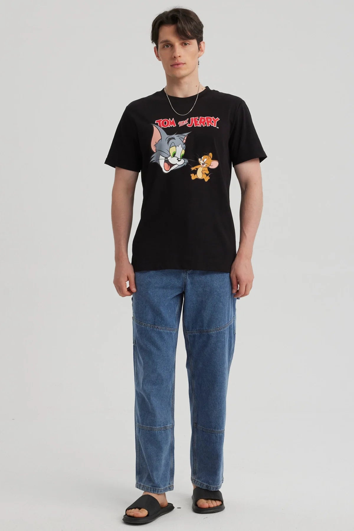 Polera negra de algodón con estampado de Tom y Jerry en estilo cartoon, mostrando a Tom con su icónica expresión y a Jerry en una pose traviesa, perfecta para fans de la clásica serie.