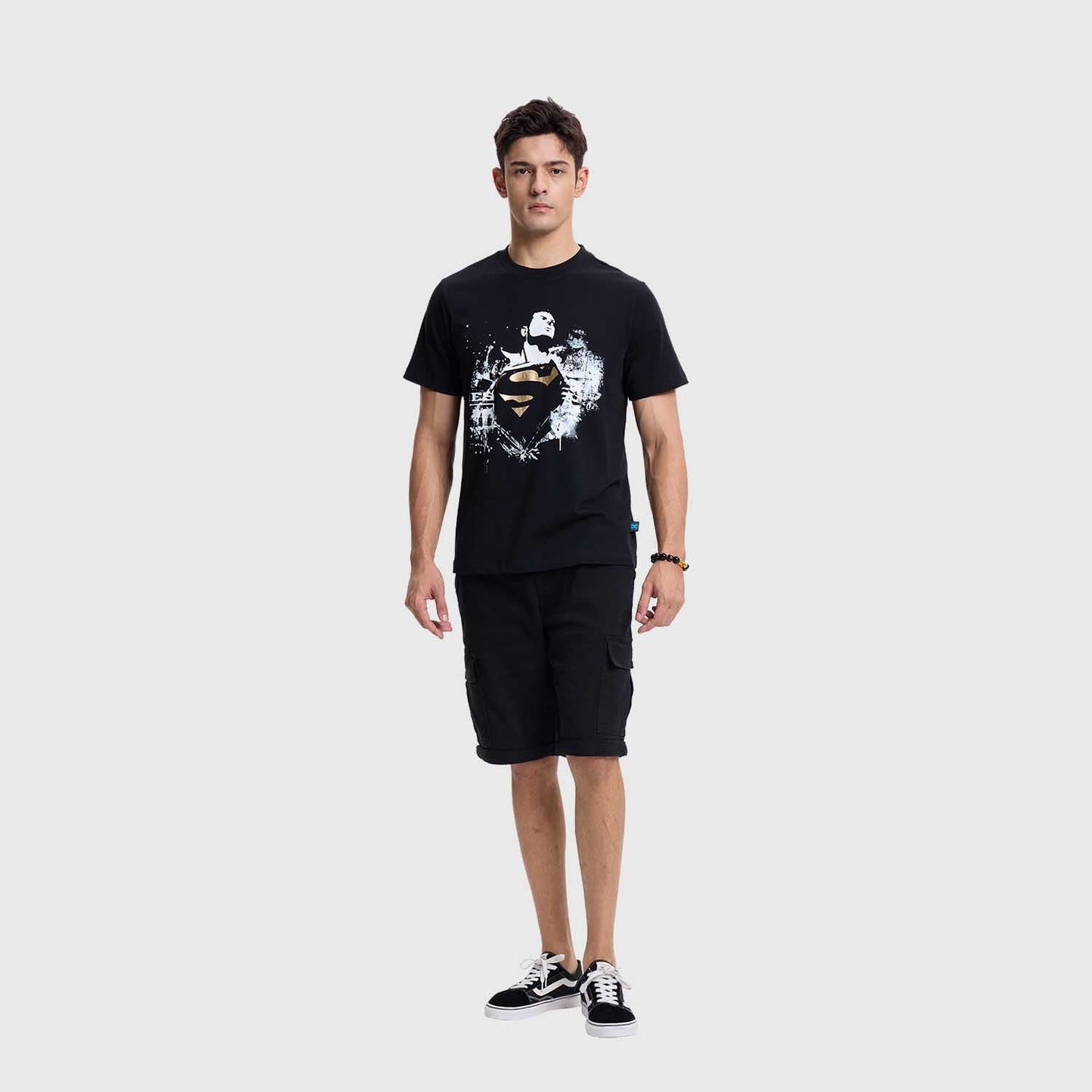 Polera negra de Superman con un diseño gráfico en blanco y dorado que muestra al héroe en pose heroica, con el logo icónico en el centro, representando su legado.
