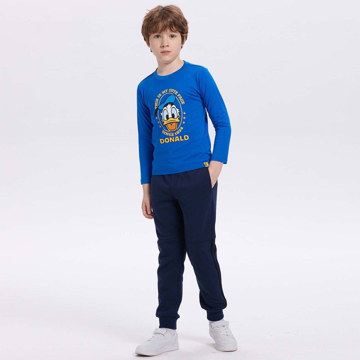 Polera azul con estampado de Pato Donald, diseño gráfico colorido que dice 'THIS IS MY CUTE FACE SINCE 1934' en un estilo divertido y juvenil.