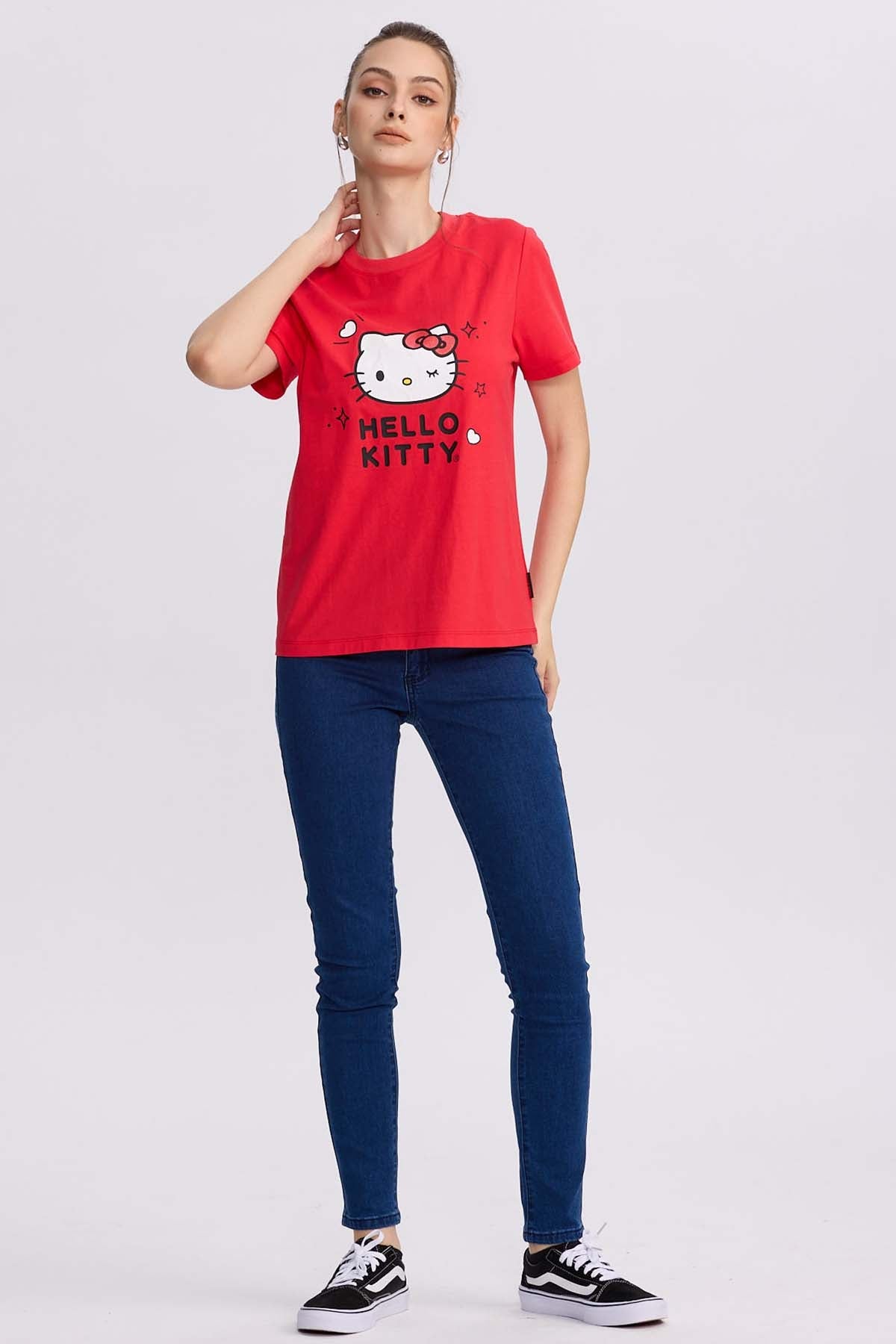 Polera roja de algodón con la icónica cara de Hello Kitty al centro, rodeada de corazones y destellos, perfecta para los fans del universo Sanrio.