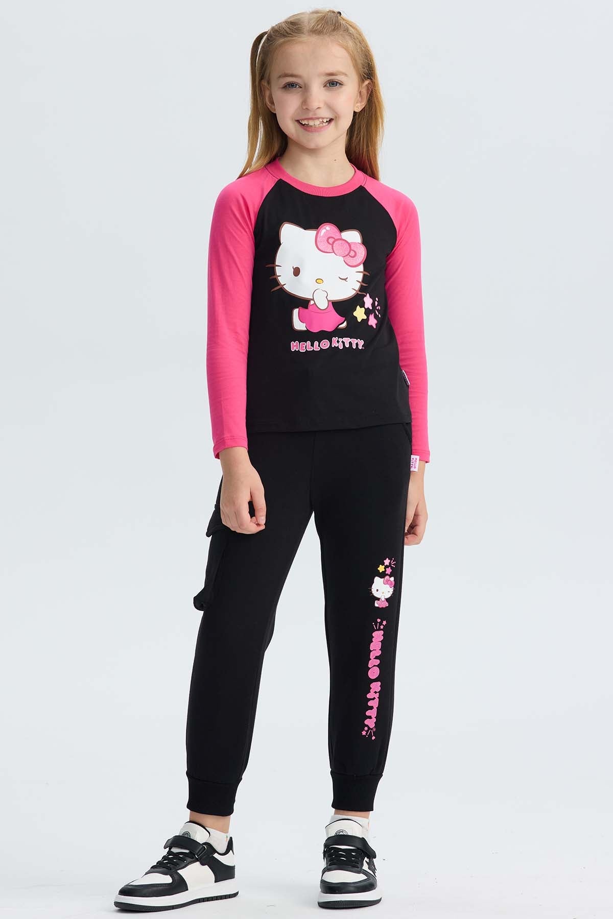 Pantalón buzo cargo negro con estampado de Hello Kitty en tonos rosa y amarillo, mostrando a la icónica gatita con su moño, ideal para fans de Sanrio.