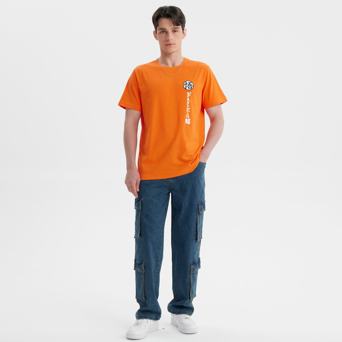Polera naranja de Dragon Ball con el símbolo de Goku en el pecho y caracteres japoneses en vertical, ideal para fans del anime.