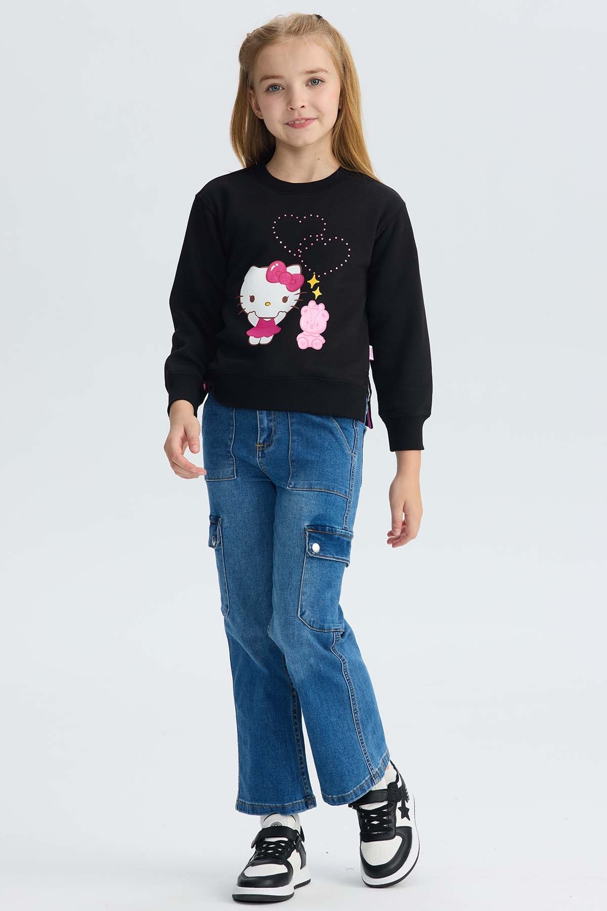 Polerón negro con ilustración de Hello Kitty en vestido rosa y un osito, decorado con brillos y corazones, ideal para fans de Sanrio.