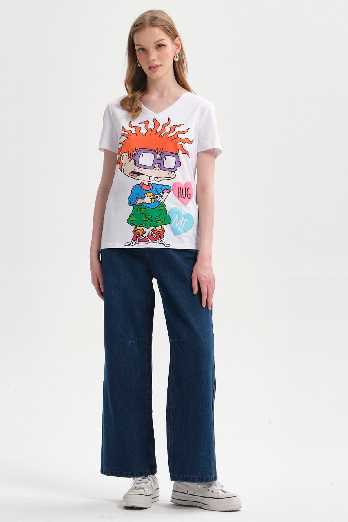 Polera blanca con la ilustración de Carlitos de Rugrats, mostrando su característico cabello rojo y gafas, acompañado de corazones que dicen 'HUG ME'.