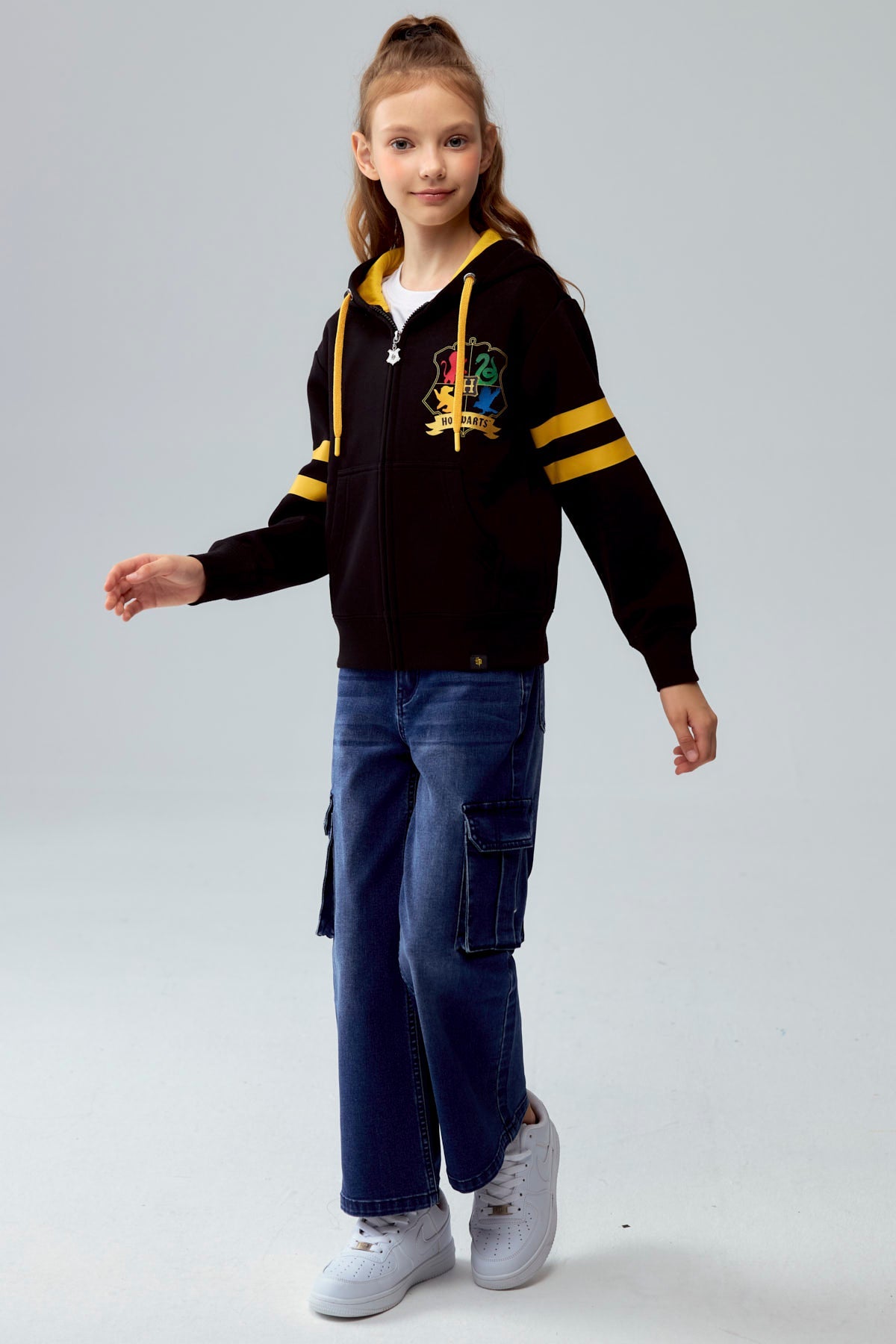 Polerón negro con capucha y detalles en amarillo, presenta el escudo de Hogwarts en el pecho y franjas en las mangas, ideal para los fans de Harry Potter.