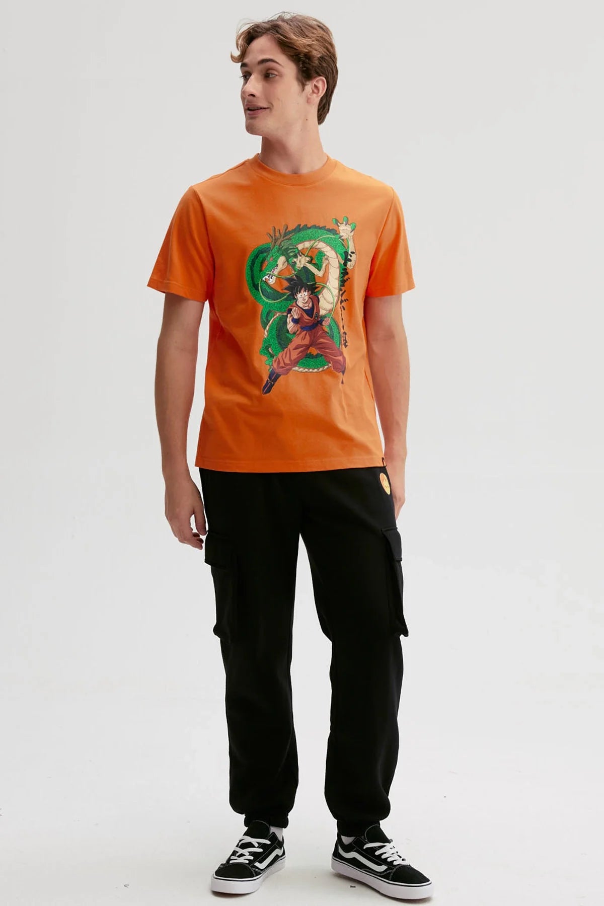 Polera naranjo de Dragon Ball con Goku en pose de combate y Shenlong detrás, ilustración vibrante que evoca la esencia del anime clásico.