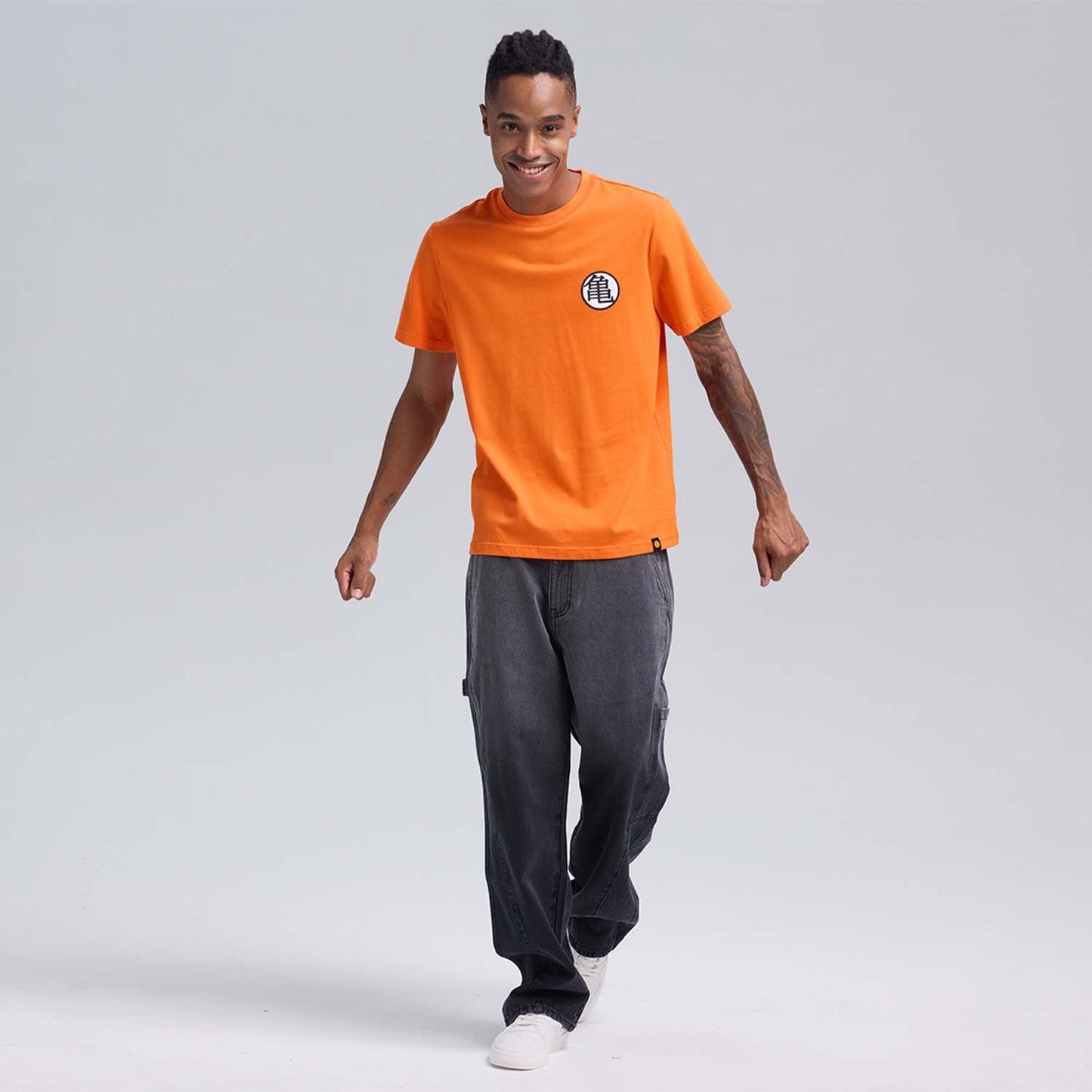 Polera naranja de Dragon Ball con el icónico símbolo de la tortuga en el pecho, confeccionada en 100% algodón, ideal para fans de la saga.