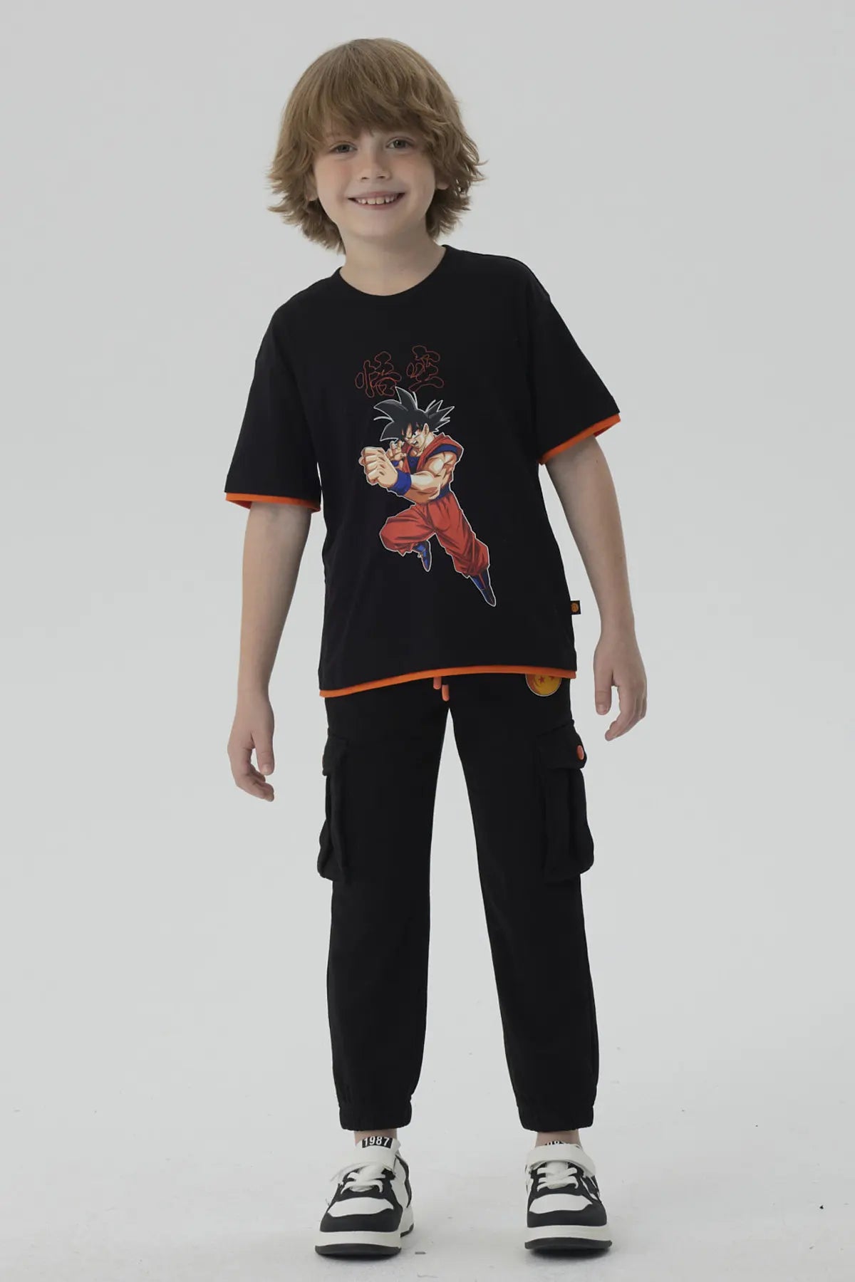 Pantalón buzo negro con detalles en naranja, presenta el icónico logo de Dragon Ball en la pierna, ideal para fans de la saga.