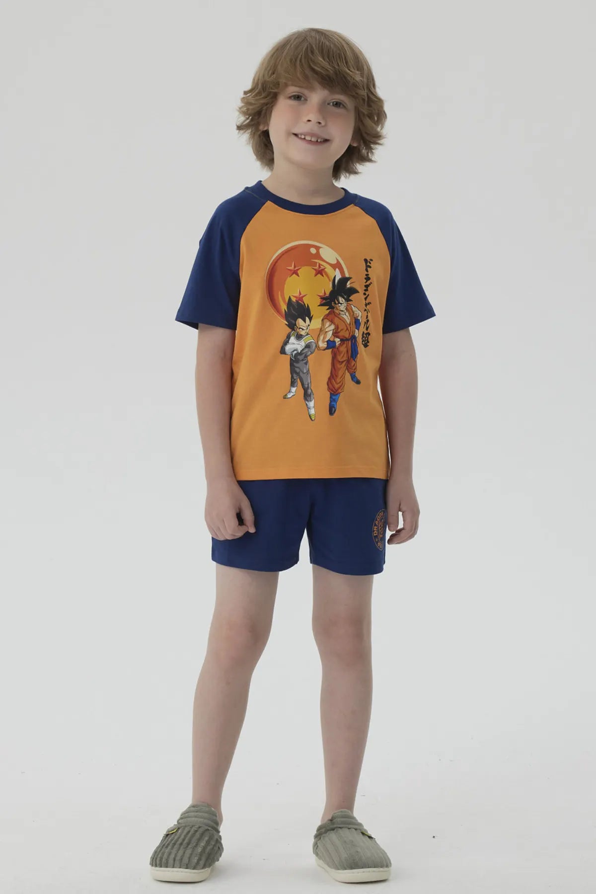 Pijama Dragon Ball azul marino con camiseta naranja que muestra a Goku y Vegeta en acción, con detalles vibrantes y logo en pantalones cortos.