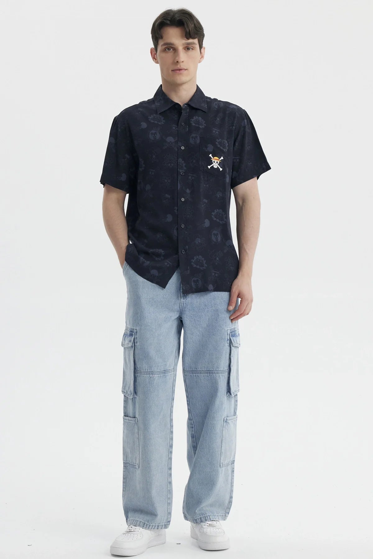 Camisa de manga corta negra con estampado sutil de personajes de One Piece, incluye el icónico logo de la tripulación de Luffy en el pecho.