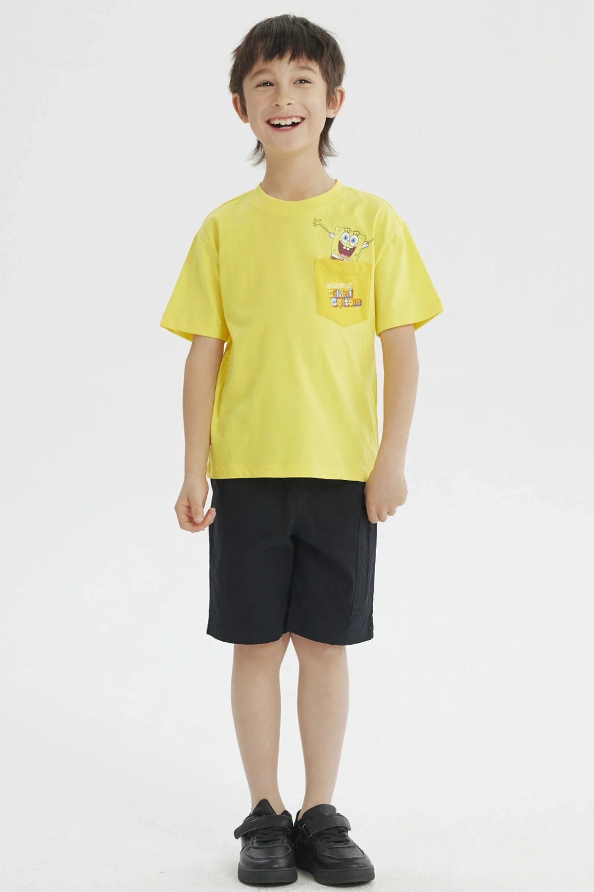Polera amarilla de algodón con un divertido diseño de Bob Esponja en el bolsillo, que dice 'Welcome to Bikini Bottom', ideal para fans de la serie.
