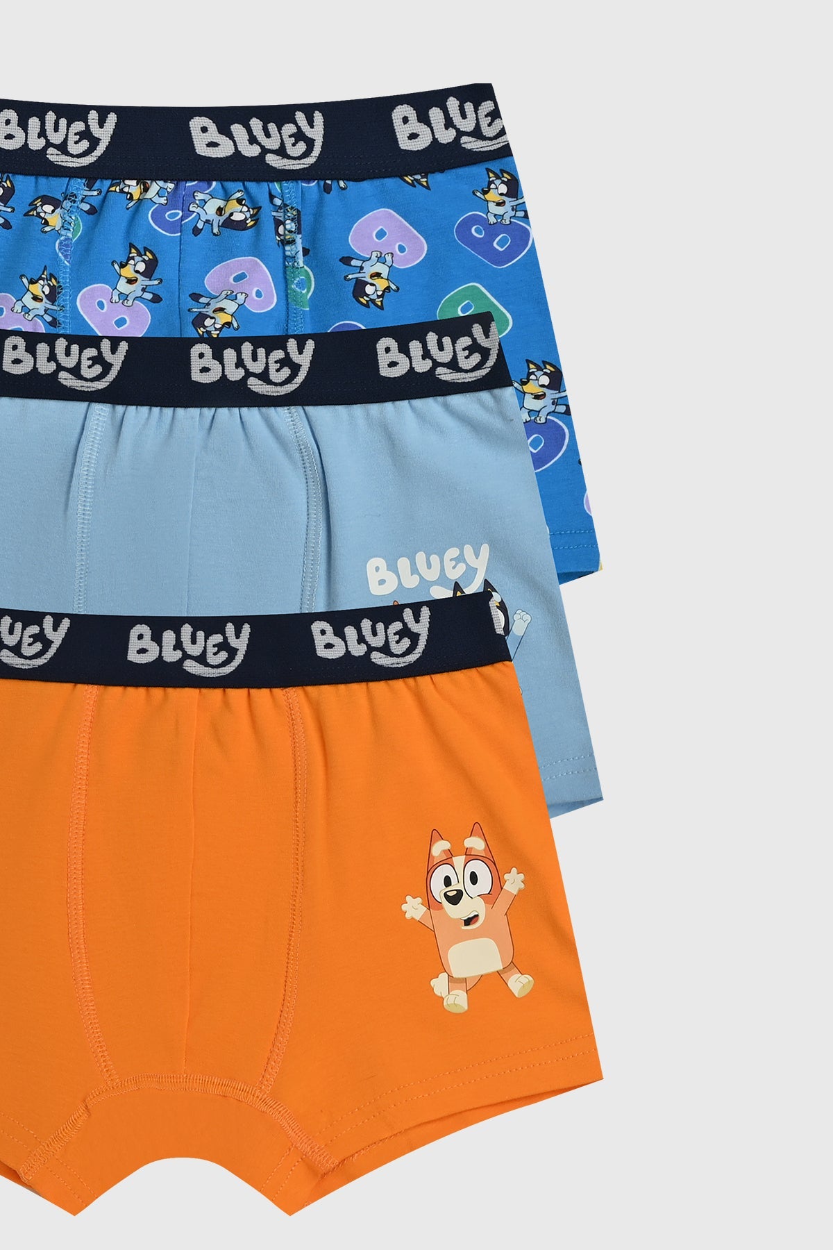 Boxer tripack celeste con estampados de Bluey, uno en naranja con Bluey saltando, otro azul claro con Bluey y Bingo, y un tercero azul marino con múltiples personajes.