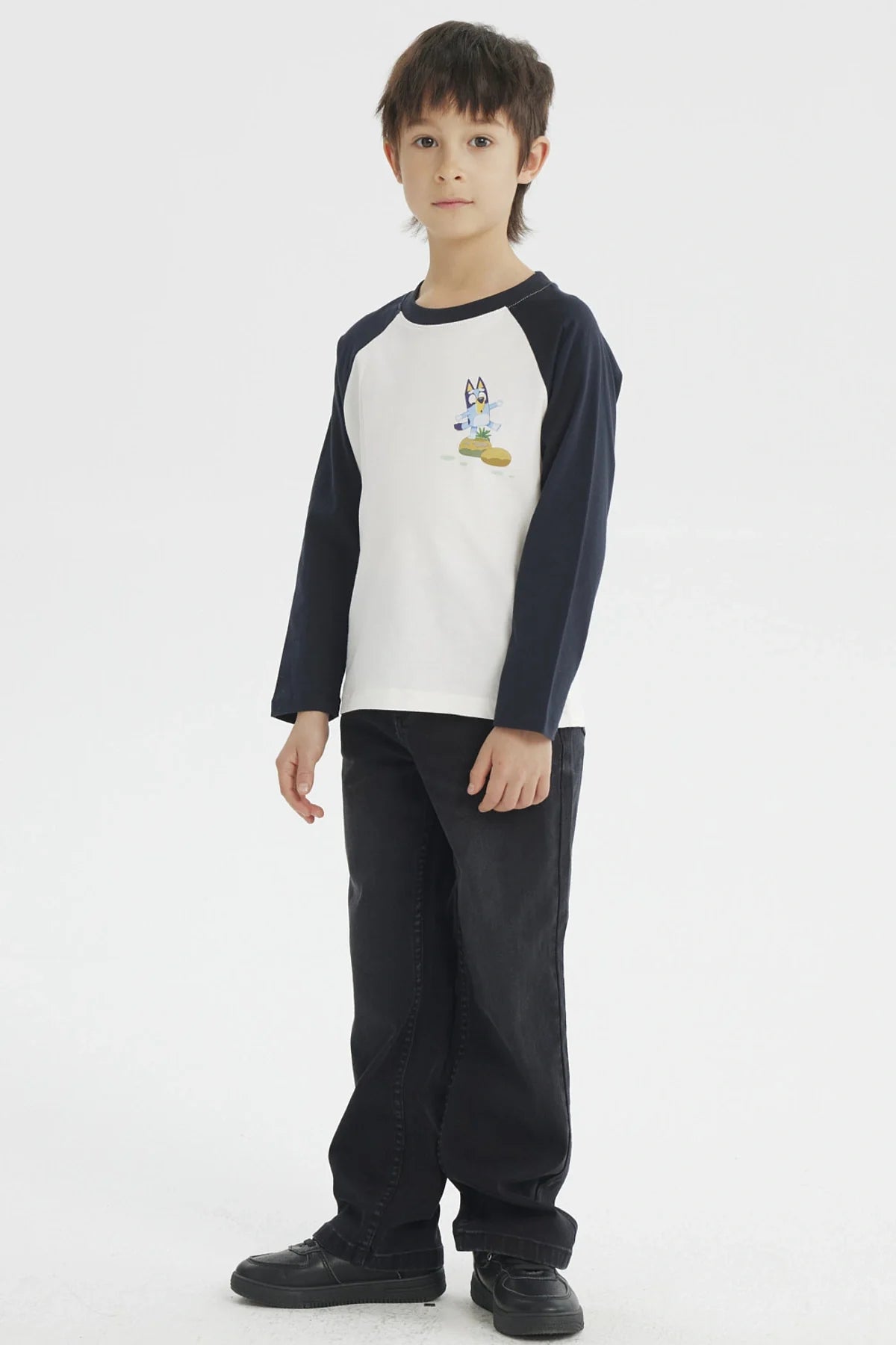 Polera de manga larga azul marino con cuerpo blanco, presenta a Bluey en acción sobre un fondo de colores suaves, ideal para fans de la serie australiana.