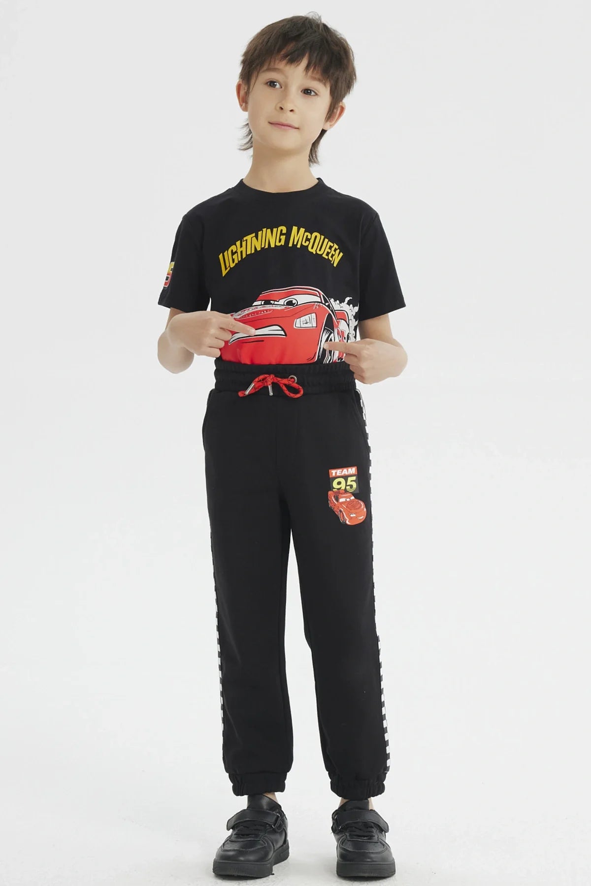 Pantalón buzo negro con detalles de 'Team 95' y un diseño vibrante de Rayo McQueen, ideal para los fans de Cars, con bandas a cuadros en los laterales.