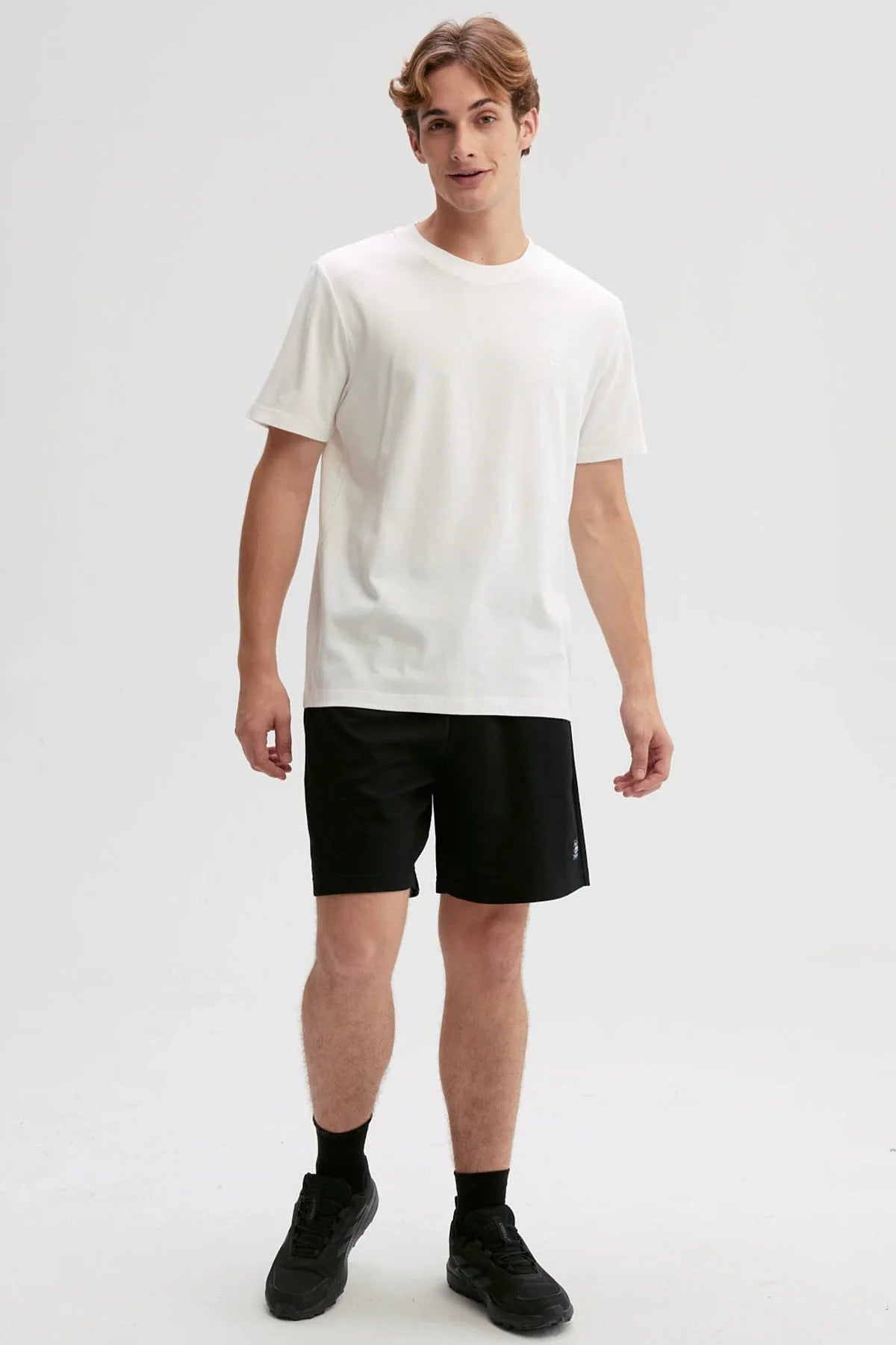 Polera blanca de algodón con diseño minimalista, presenta un logo sutil en el pecho, ideal para fans de la moda casual y contemporánea.