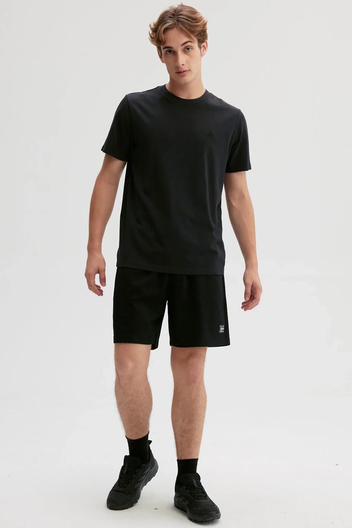 Polera negra de algodón con un diseño minimalista que presenta un logo sutil en el pecho, ideal para los fans de la moda urbana y el estilo casual.