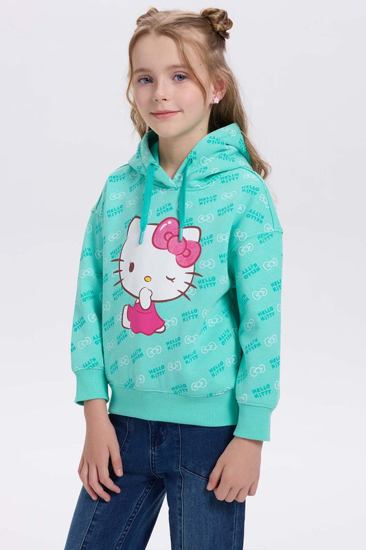 Polerón verde menta con estampado de Hello Kitty en el centro, mostrando su icónica pose con vestido rosa y fondo de patrones de la marca.