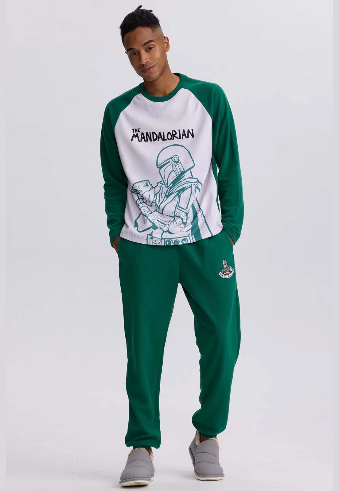 Pijama Mandalorian verde musgo con camiseta blanca y detalles en verde, presenta ilustración de Mando sosteniendo a Grogu, ideal para fans de Star Wars.