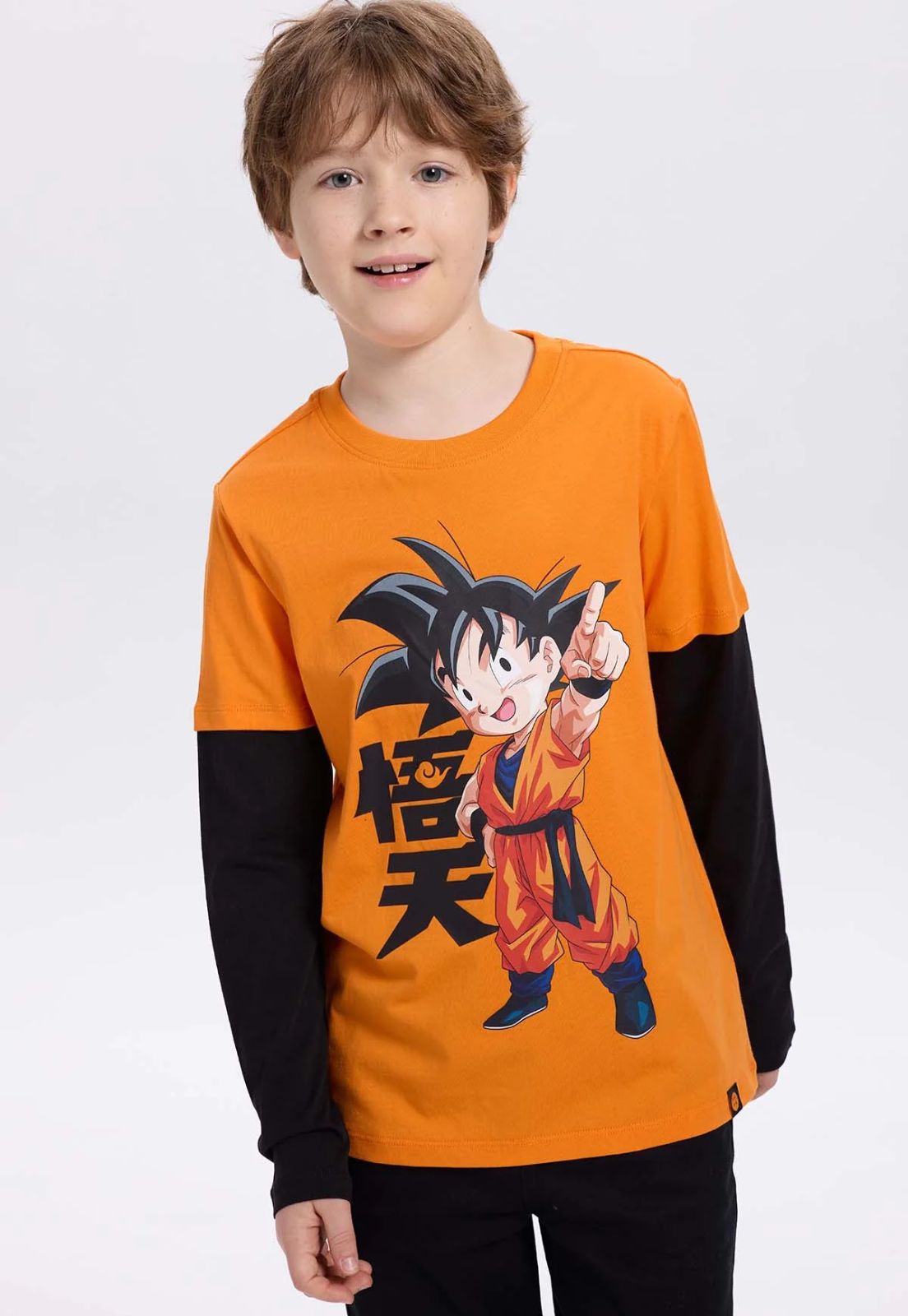 Polera naranja de Dragon Ball con ilustración de Goku en pose dinámica, fondo negro con caracteres kanji, perfecta para fans de la saga.