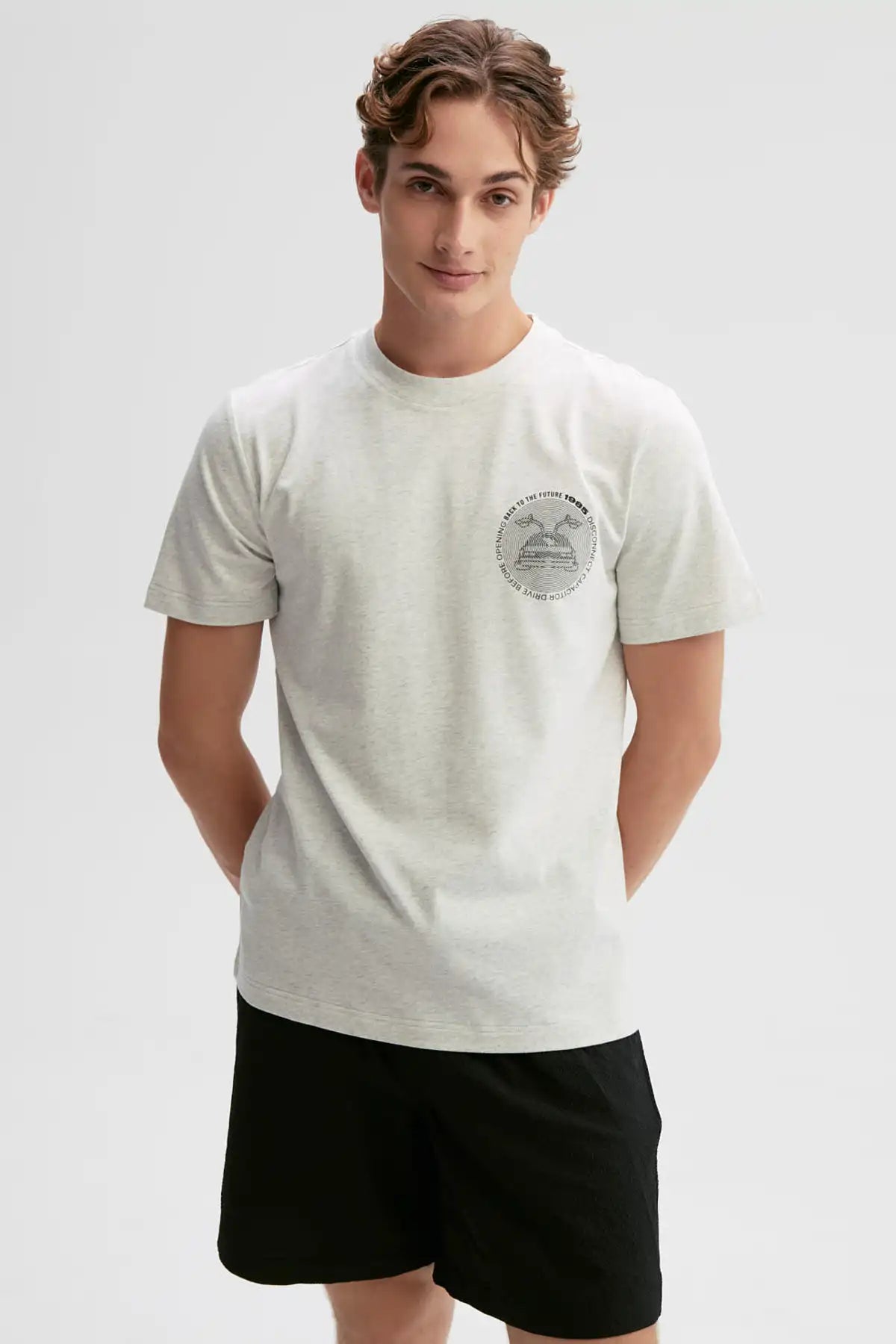 Polera gris de algodón con un diseño minimalista que presenta la icónica DeLorean de 'Volver al Futuro' y el texto 'Roads? Where we're going we don't need roads'.