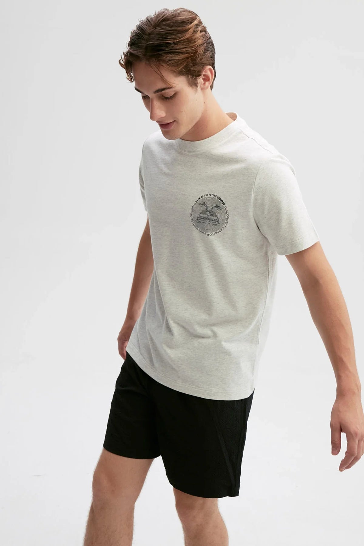 Polera gris de algodón con un diseño minimalista que presenta la icónica DeLorean de 'Volver al Futuro' y el texto 'Roads? Where we're going we don't need roads'.