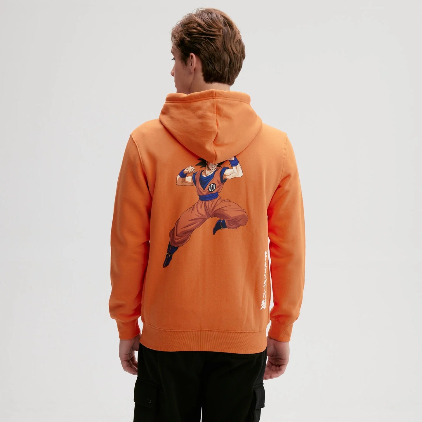 Polerón naranjo de Dragon Ball con capucha, presenta el icónico símbolo de Goku en el pecho, ideal para fans del universo Shonen.