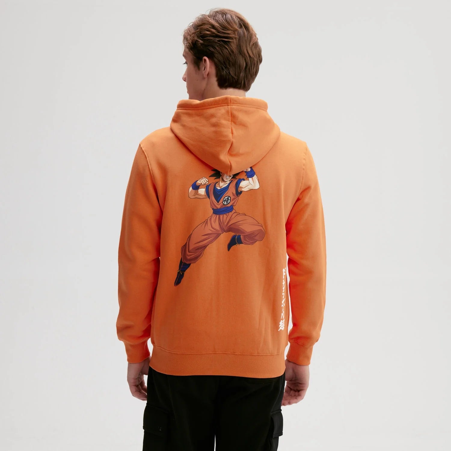 Polerón naranjo de Dragon Ball con capucha, presenta el icónico símbolo de Goku en el pecho, ideal para fans del universo Shonen.