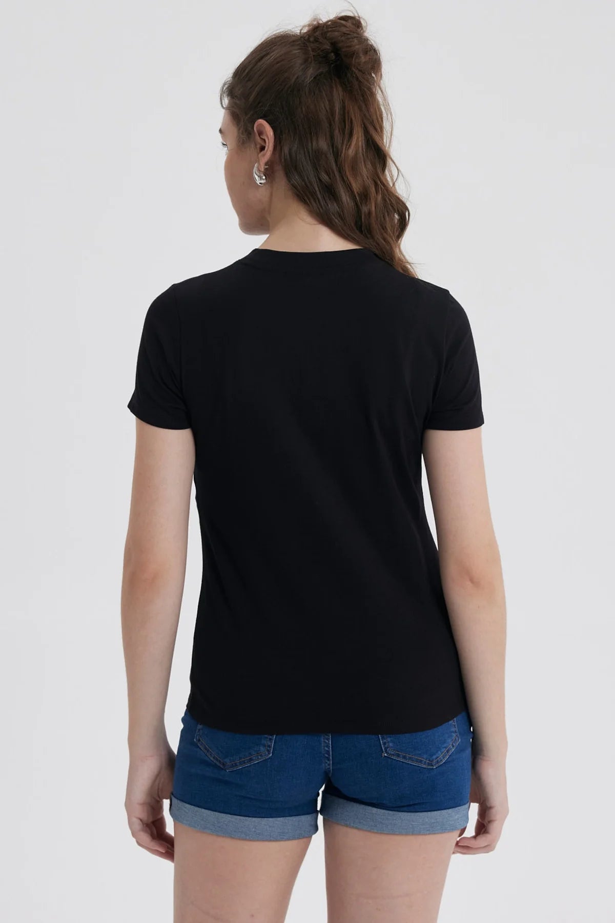Polera negra de algodón con la icónica ilustración de Pequeña Lulú sonriendo y rodeada de corazones, destacando su vestido rojo y su peinado característico.
