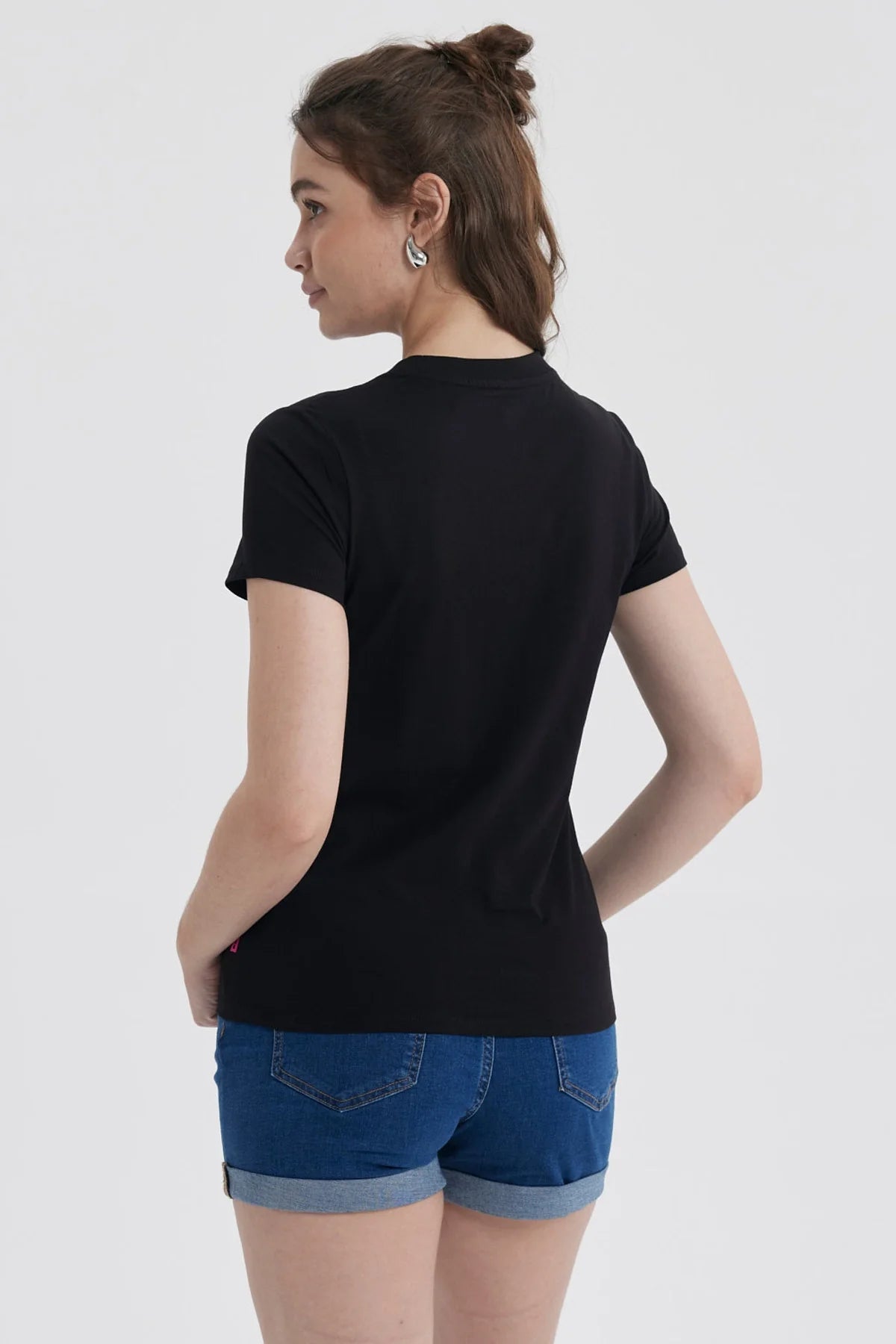 Polera negra de algodón con estampado de Kuromi, personaje de Sanrio, sentada en un sillón rosa con un té, rodeada de detalles en rosa y texto 'KUROMI IS ALWAYS IN STYLE'.