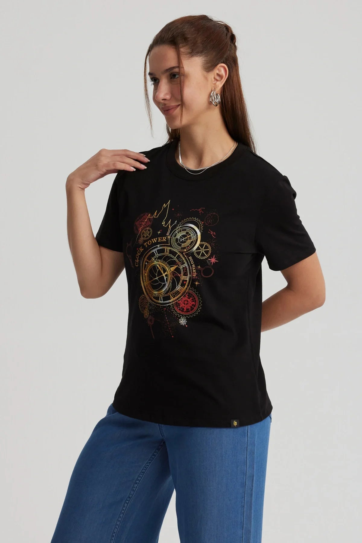 Polera negra de algodón con un diseño dorado y rojo que muestra la icónica torre del reloj de Hogwarts, evocando la magia de Harry Potter.