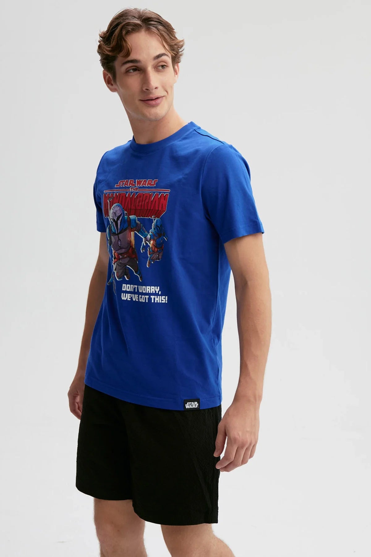 Polera azul con ilustración vibrante de Mandalorian y su equipo en acción, destacando el lema "Don't worry, we've got this!" en un estilo retro.