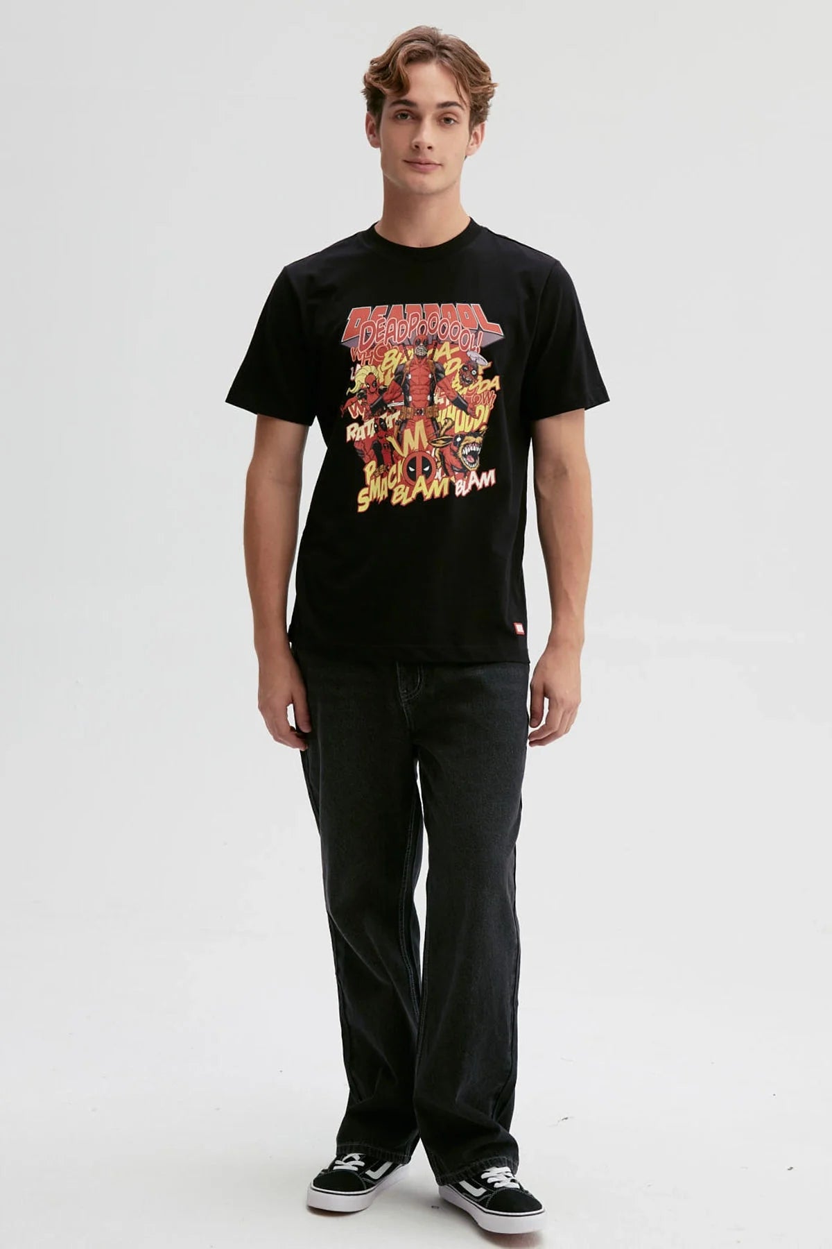 Polera negra de Deadpool con ilustración vibrante en rojo y amarillo, mostrando al antihéroe en acción con onomatopeyas cómicas, ideal para fans de Marvel.