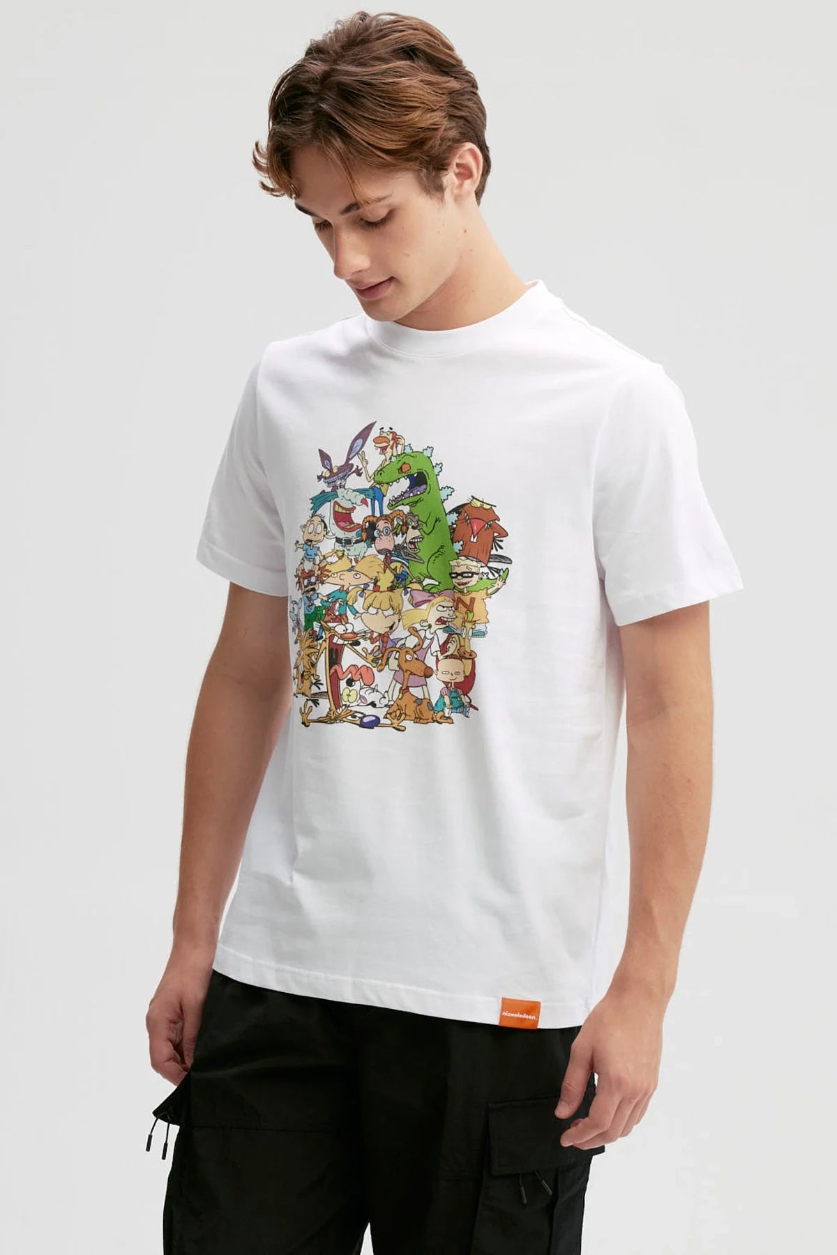 Polera blanca de algodón con un vibrante estampado de personajes icónicos de Nickelodeon, incluyendo a Tommy y Reptar, en una colorida ilustración que celebra la nostalgia.