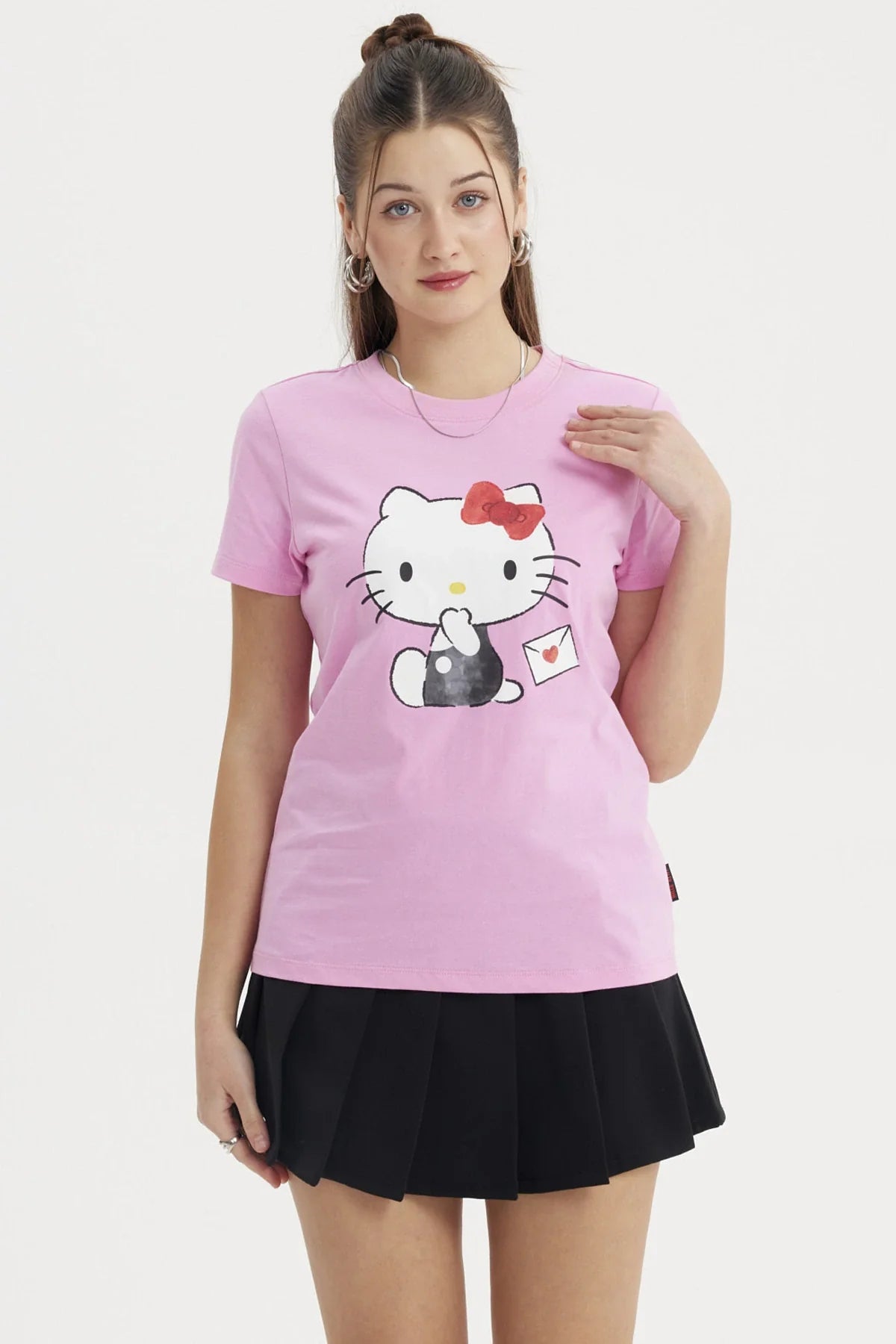 Polera rosada de algodón con ilustración de Hello Kitty en pose adorable, sosteniendo una carta con un corazón, ideal para fans del universo Sanrio.