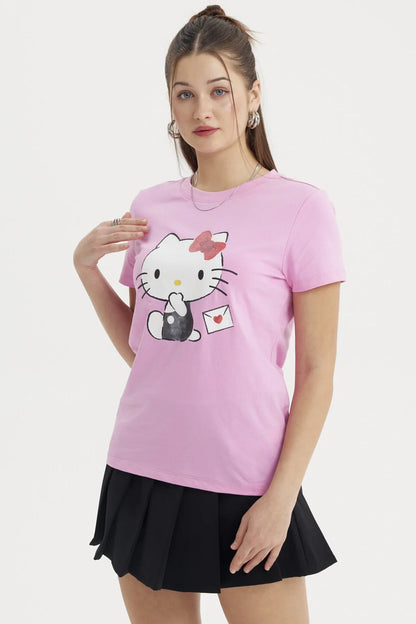 Polera rosada de algodón con ilustración de Hello Kitty en pose adorable, sosteniendo una carta con un corazón, ideal para fans del universo Sanrio.