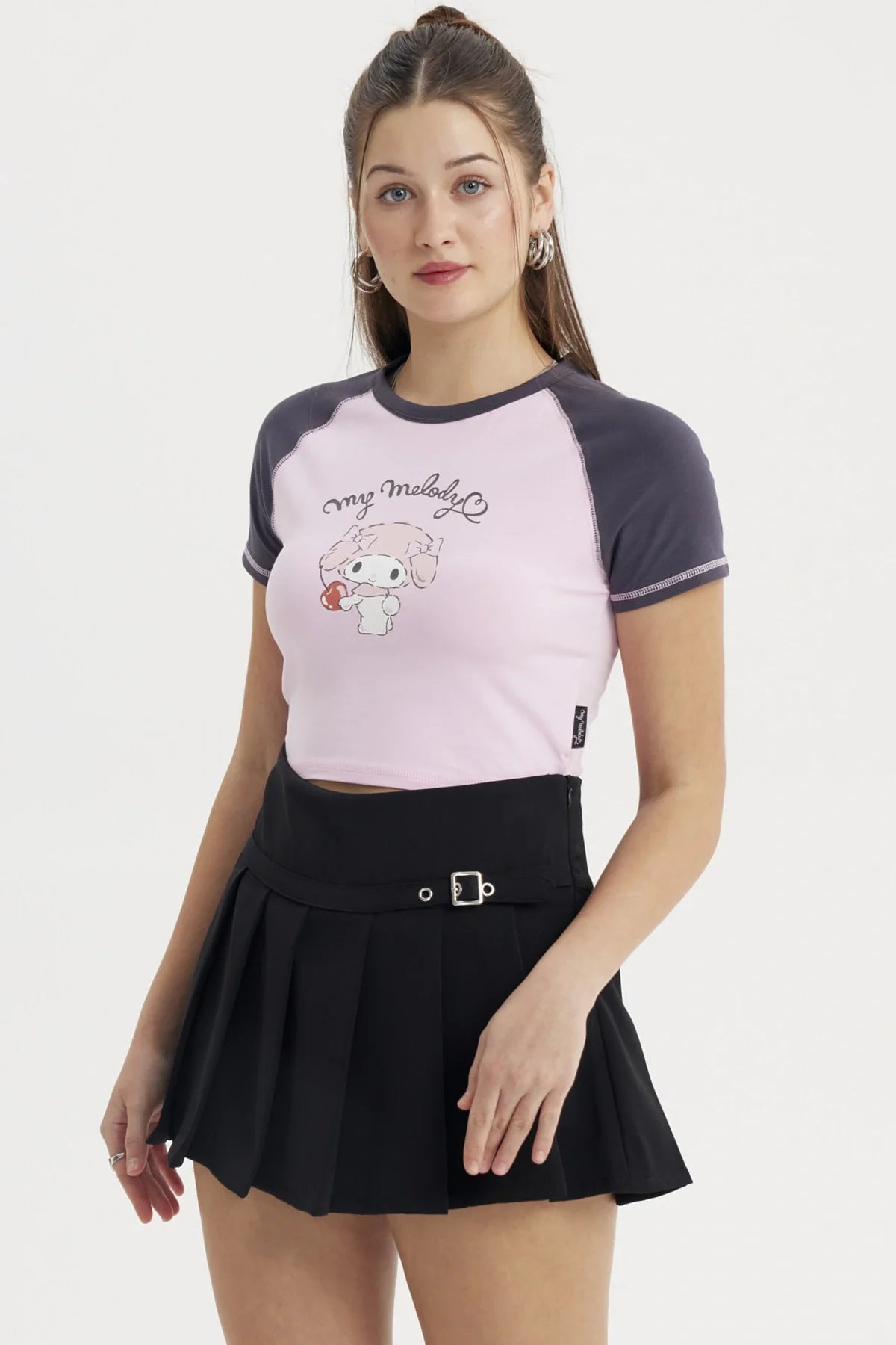 Polera rosa de My Melody con detalles en azul marino, presenta una ilustración de la adorable conejita sosteniendo un dulce, ideal para fans de Sanrio.
