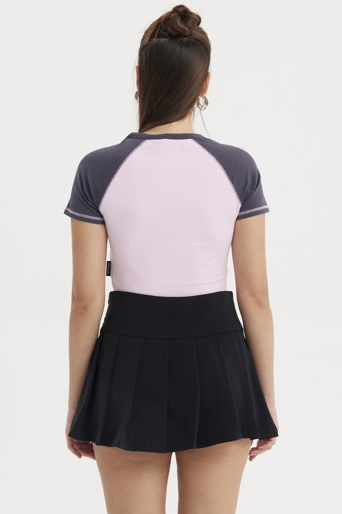 Polera rosa de My Melody con detalles en azul marino, presenta una ilustración de la adorable conejita sosteniendo un dulce, ideal para fans de Sanrio.