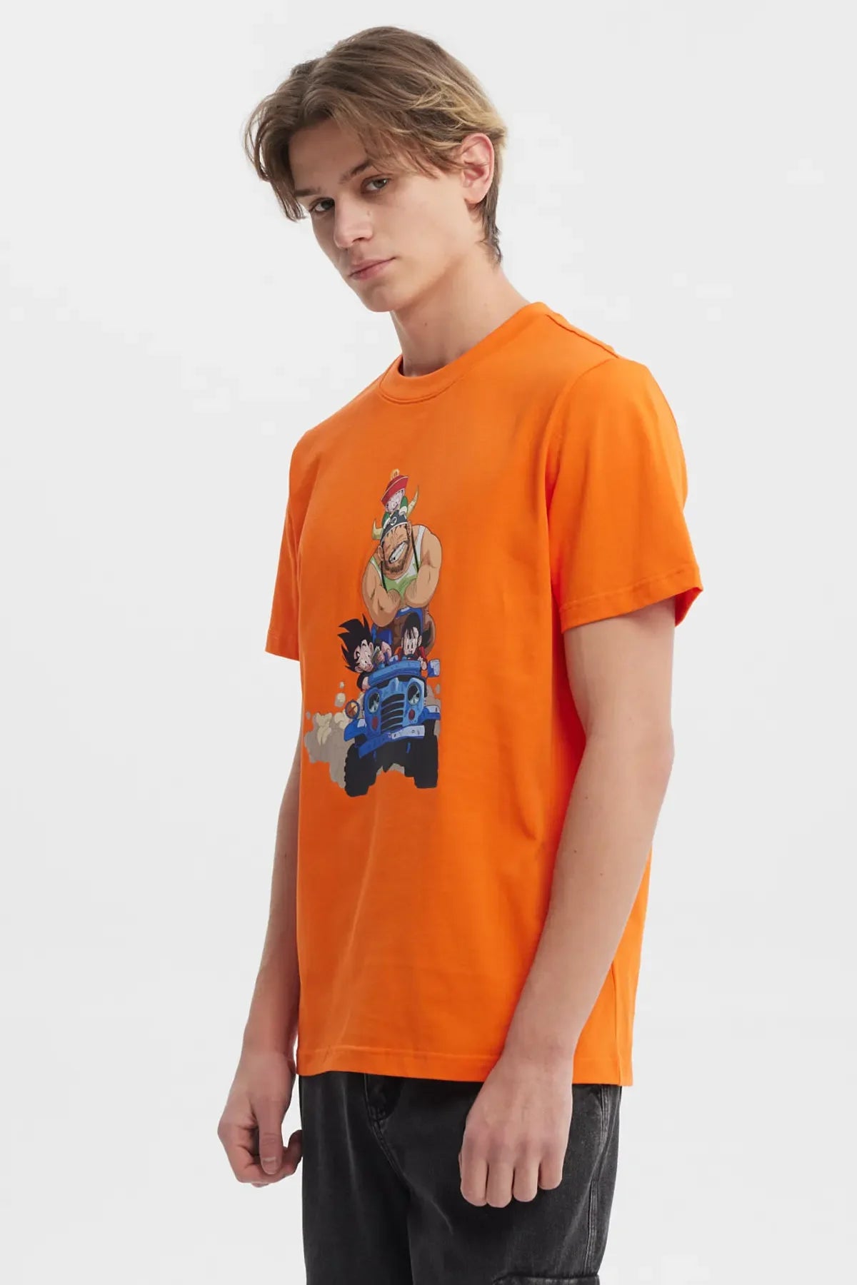Polera naranja de Dragon Ball Z con ilustración colorida de Goku, Krillin y el Maestro Roshi en un jeep, evocando la aventura y camaradería del universo de Akira Toriyama.