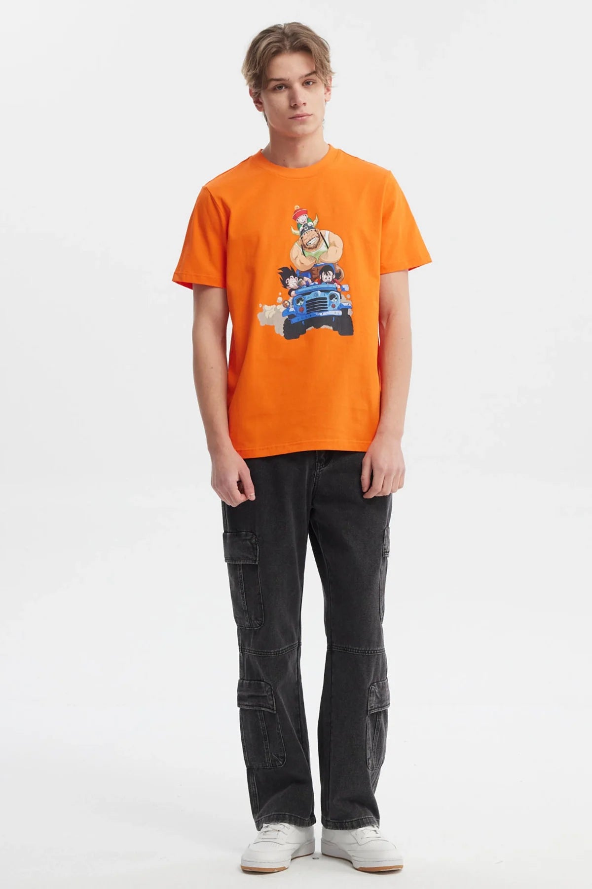 Polera naranja de Dragon Ball Z con ilustración colorida de Goku, Krillin y el Maestro Roshi en un jeep, evocando la aventura y camaradería del universo de Akira Toriyama.