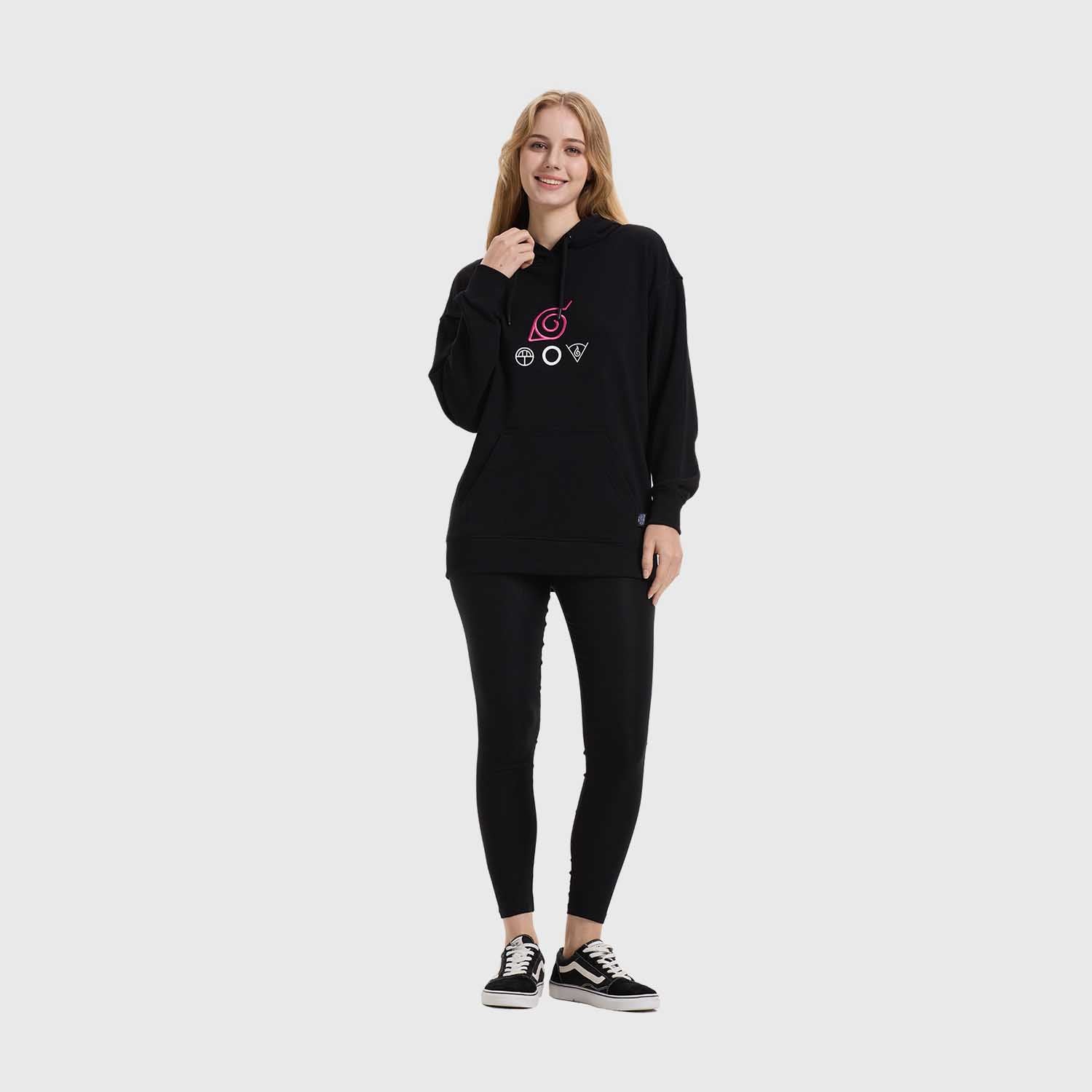 Polerón negro con capucha que presenta un diseño minimalista en tonos rosa y blanco, mostrando el símbolo de Konoha y emblemas de los clanes Uchiha y Hyuga, ideal para fans de Naruto.