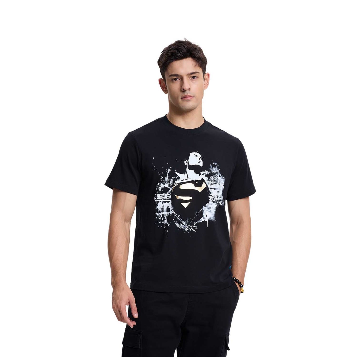 Polera negra de Superman con un diseño gráfico en blanco y dorado que muestra al héroe en pose heroica, con el logo icónico en el centro, representando su legado.