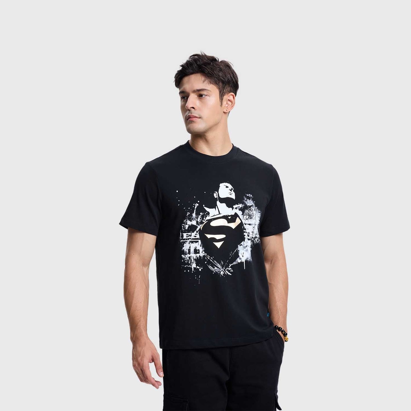 Polera negra de Superman con un diseño gráfico en blanco y dorado que muestra al héroe en pose heroica, con el logo icónico en el centro, representando su legado.