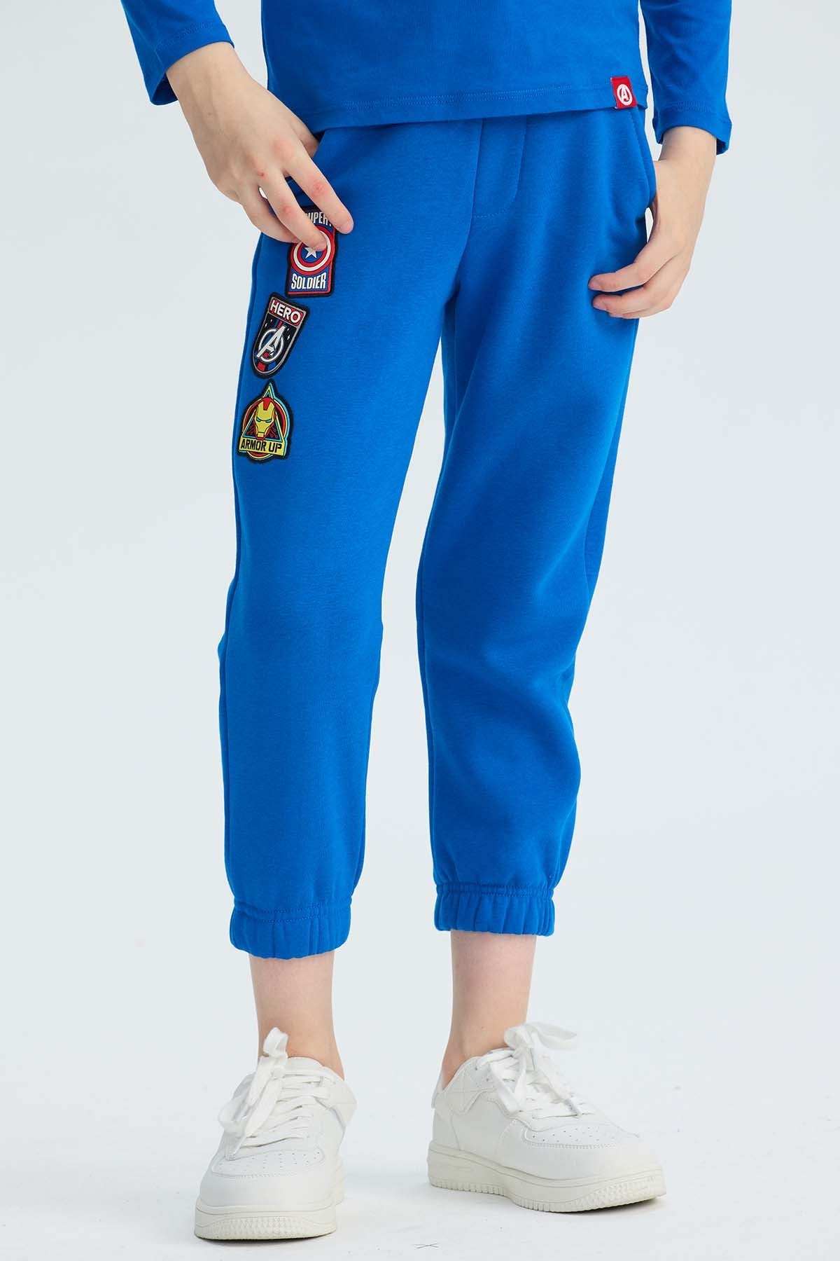 Pantalón buzo azul vibrante con parches de Avengers que destacan el heroísmo, ideal para jóvenes fanáticos de Marvel que buscan comodidad y estilo.