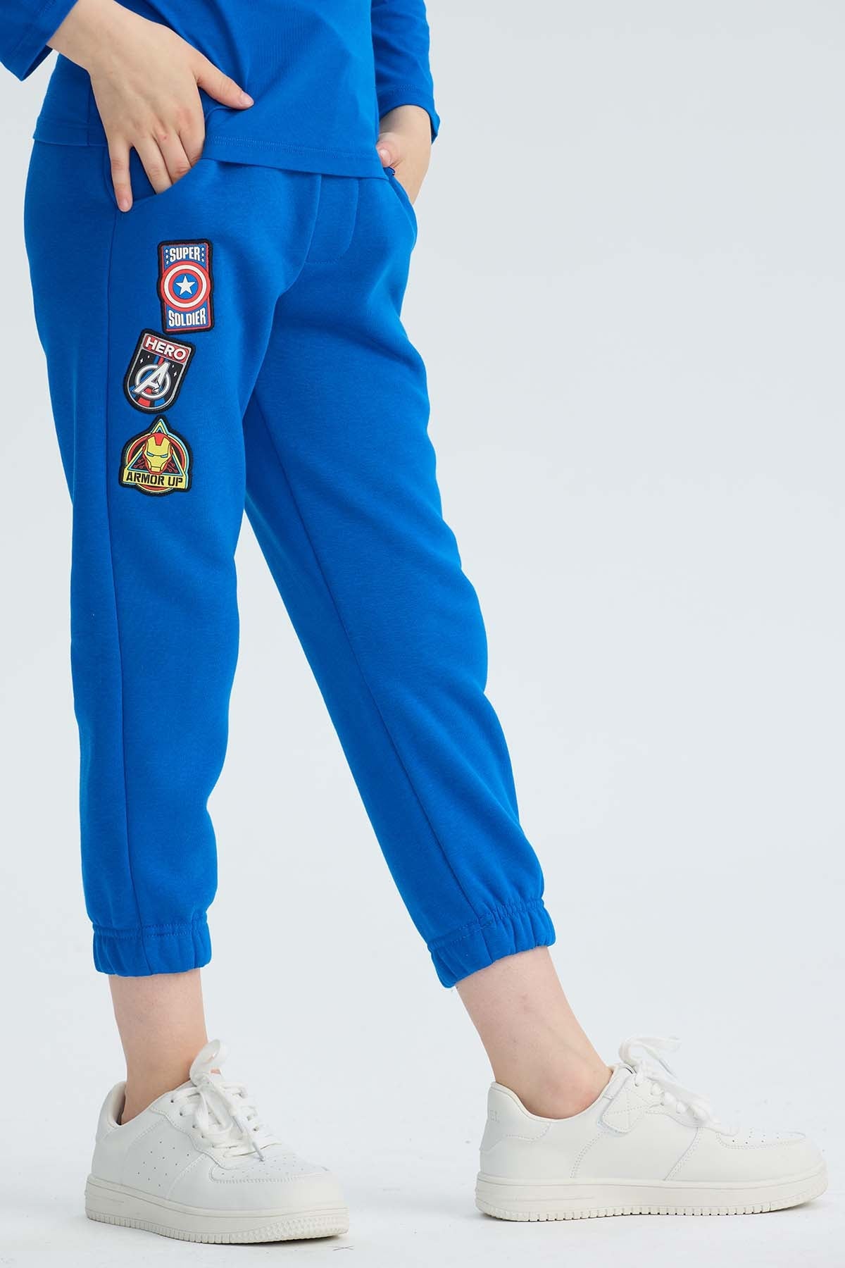 Pantalón buzo azul vibrante con parches de Avengers que destacan el heroísmo, ideal para jóvenes fanáticos de Marvel que buscan comodidad y estilo.