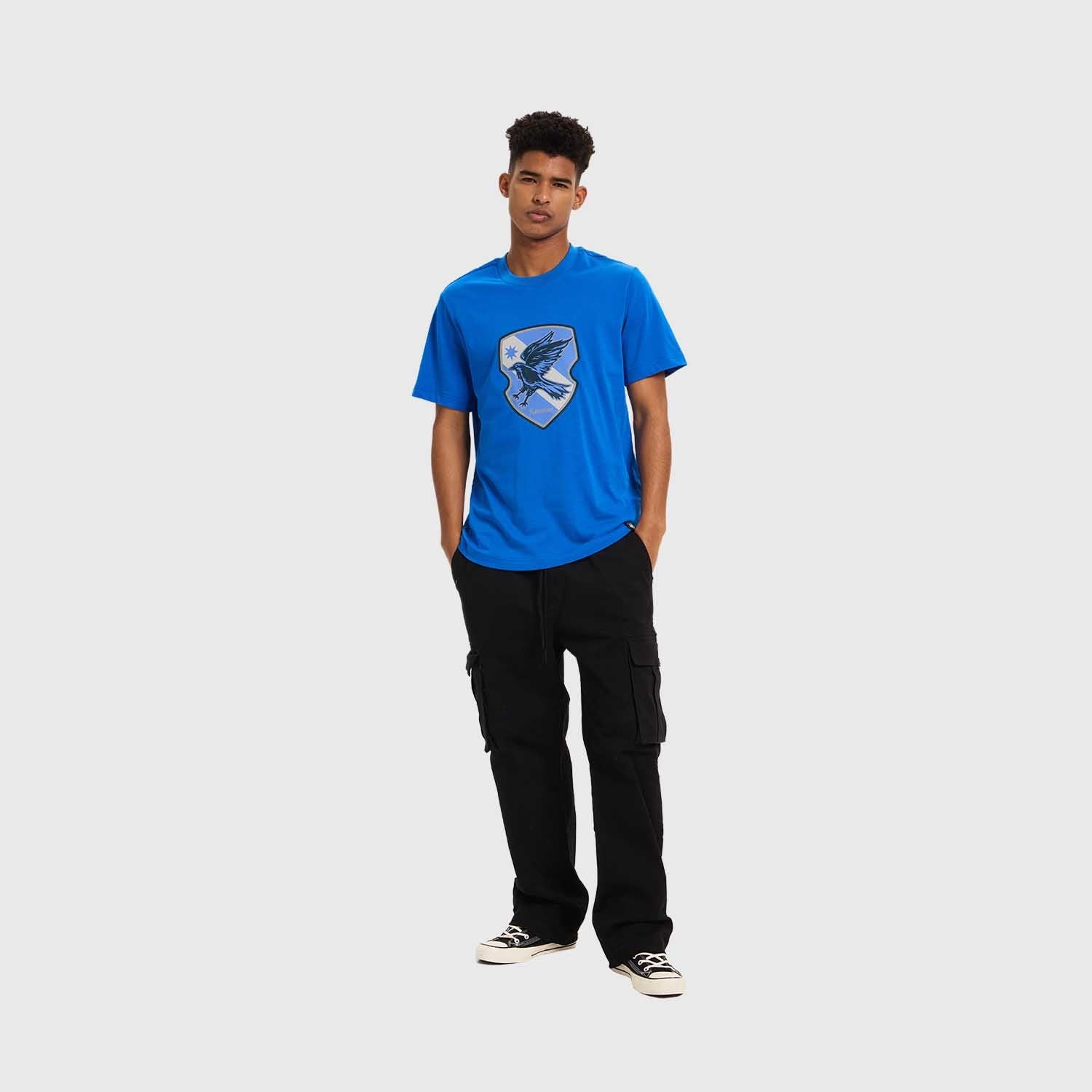 Polera azul vibrante de Ravenclaw con un escudo que presenta un águila en vuelo, símbolo de sabiduría y creatividad, ideal para los fans de Harry Potter.